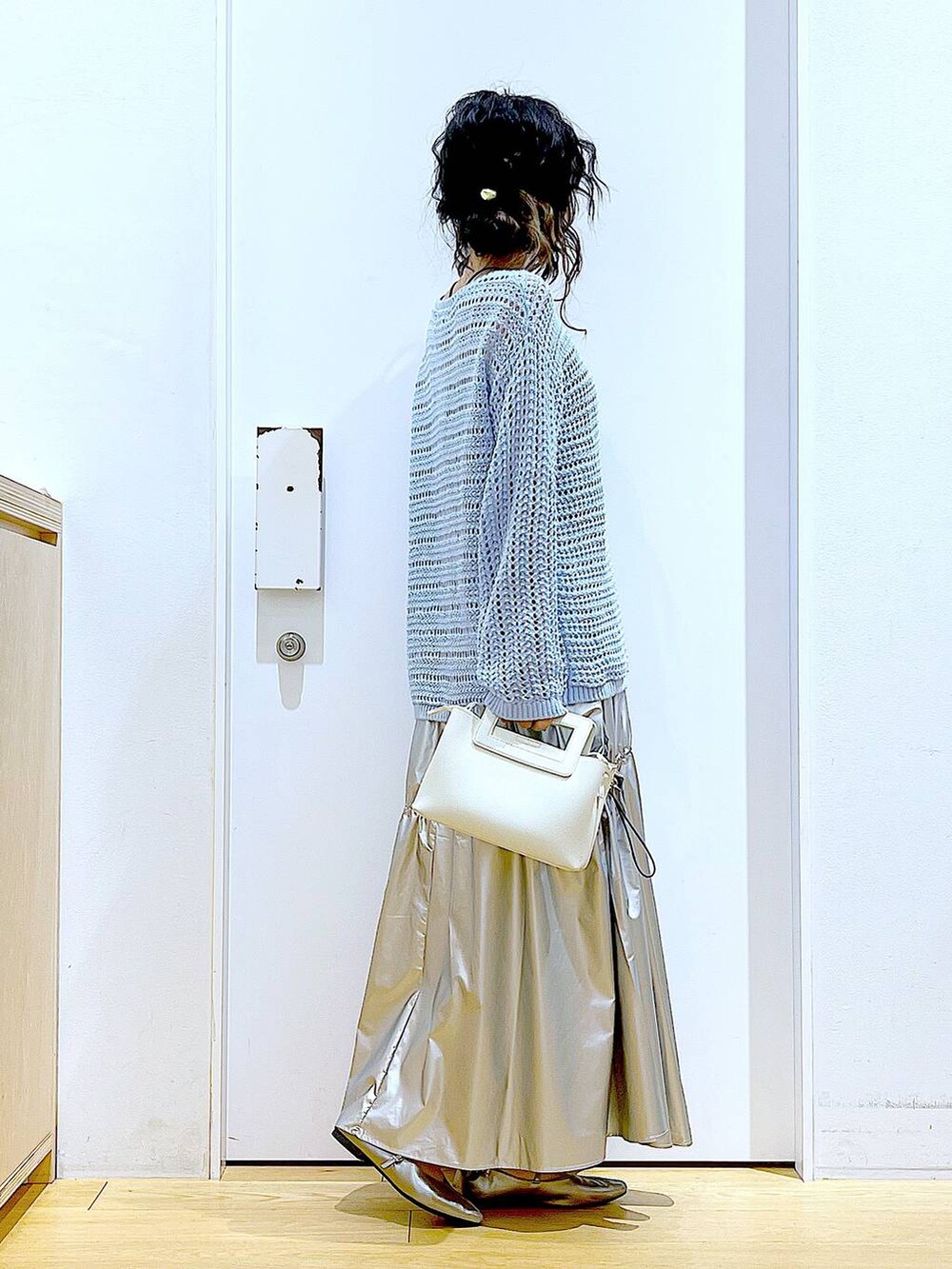 ブルー系のニット/セーター、シルバー系のスカート、ホワイト系のショルダーバッグを着用したレディースの春コーディネートの4枚目の写真
