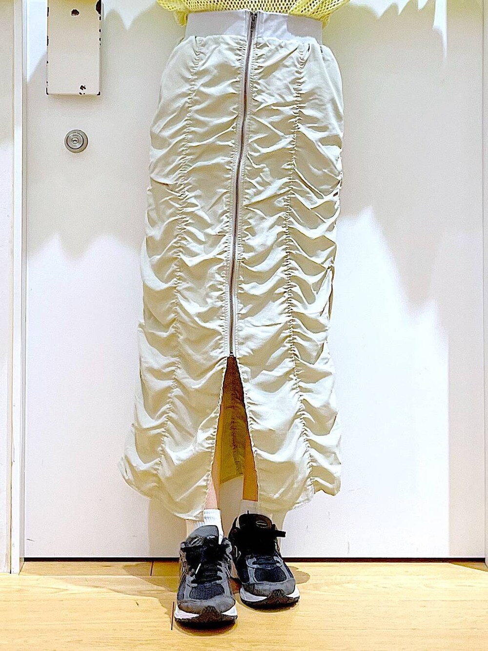 ベージュ系のスカート、ブラック系のバックパック/リュック、イエロー系のTシャツ/カットソーを着用したレディースの春コーディネートの8枚目の写真