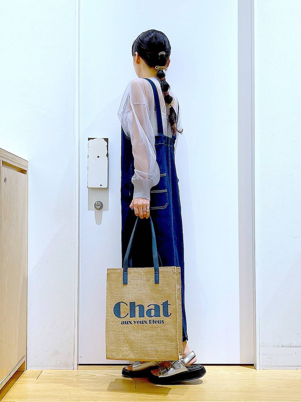 ブルー系のジャンパースカート、ブルー系のトートバッグ、シルバー系のサンダルを着用したレディースの夏コーディネートの3枚目の写真