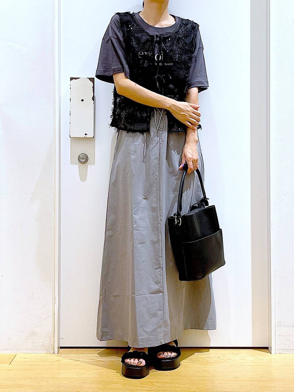 ブラック系のサンダル、ブラック系のショルダーバッグ、グレー系のスカートを着用したレディースの秋コーディネートの6枚目の写真