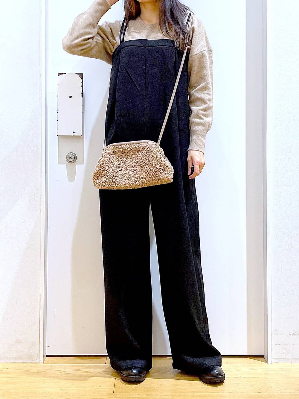 ベージュ系のニット/セーター、ブラック系のブーツ、ブラウン系のクラッチバッグを着用したレディースの冬コーディネートの6枚目の写真