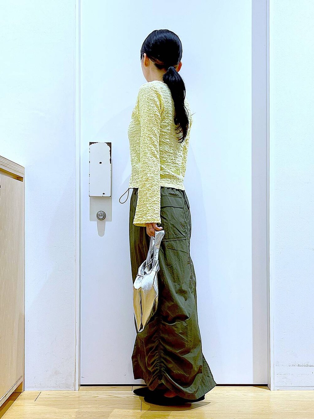 シルバー系のショルダーバッグ、グリーン系のスカート、ブラック系のパンプスを着用したレディースの春コーディネートの3枚目の写真