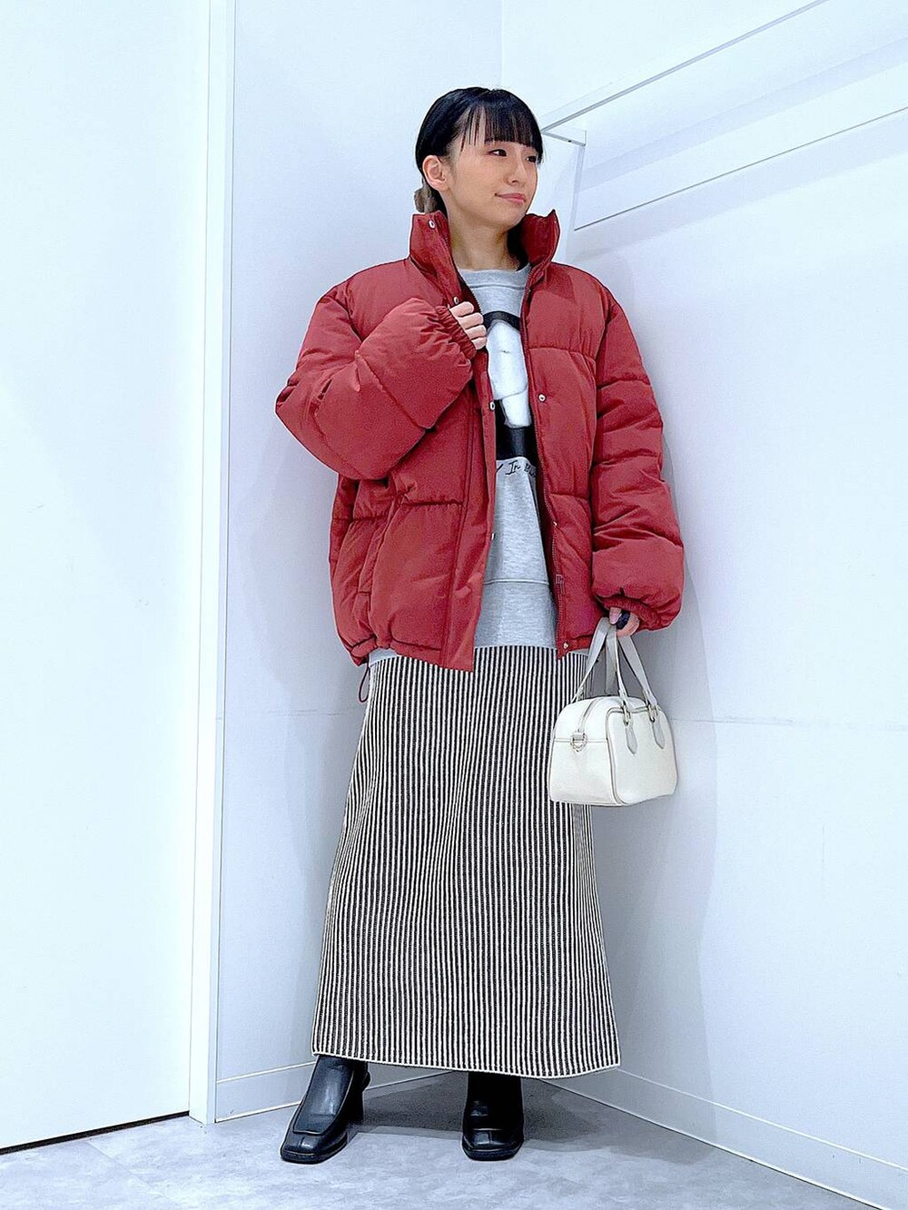 ブラウン系のブルゾン、ベージュ系のスカート、ブラック系のブーツを着用したレディースの冬コーディネートの2枚目の写真