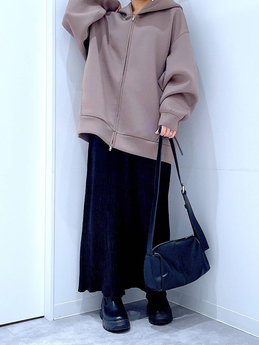 ブラック系のショルダーバッグ、ブラック系のブーツ、ブラウン系のパーカーを着用したレディースの秋コーディネートの6枚目の写真