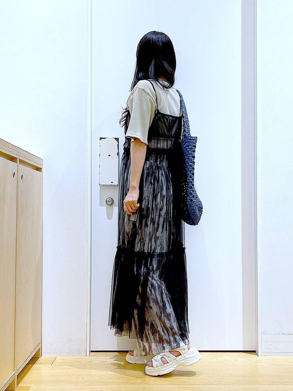 ブラック系のワンピース、ホワイト系のサンダル、ブルー系のトートバッグを着用したレディースの夏コーディネートの3枚目の写真