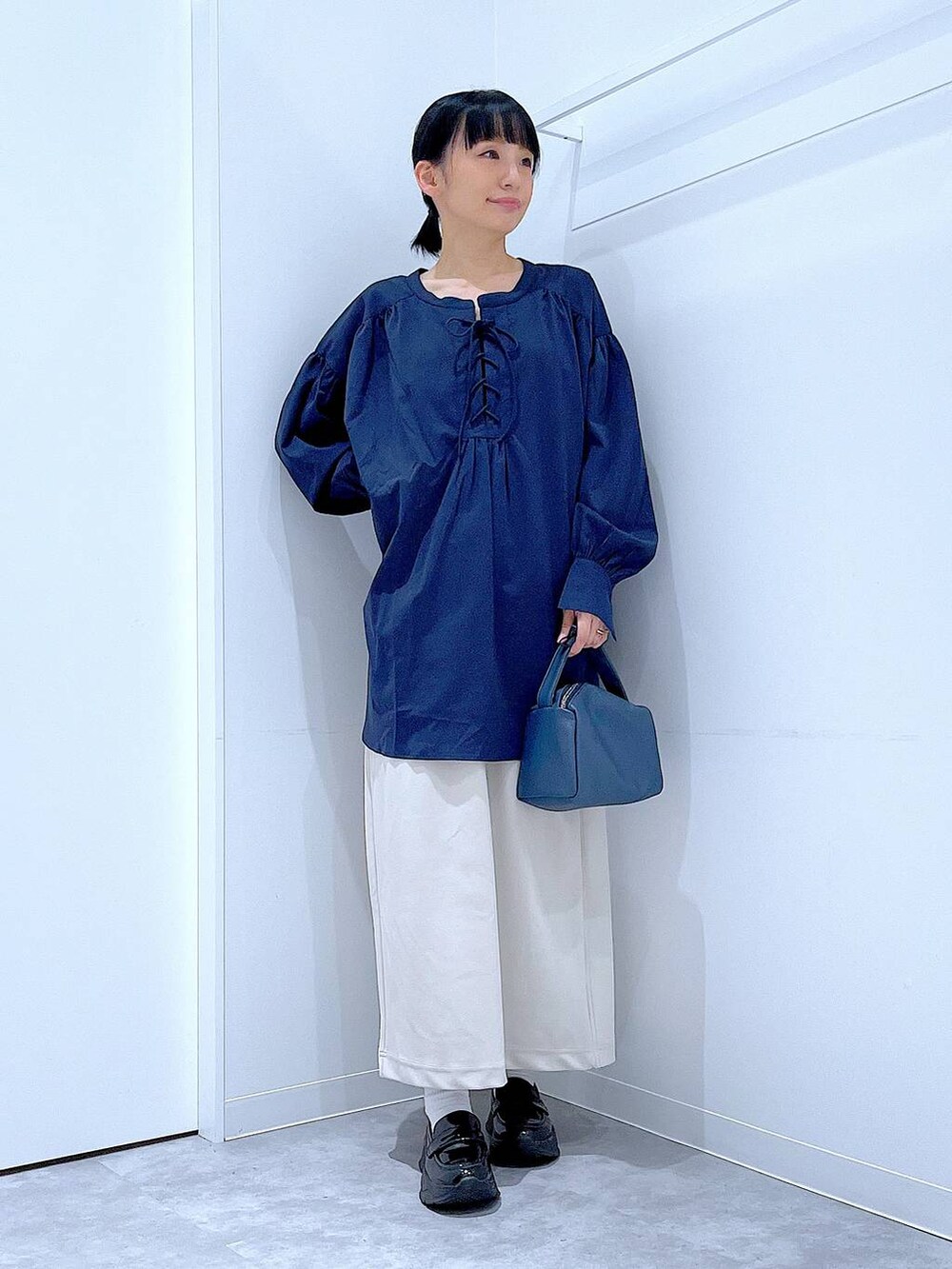 ベージュ系のスカート、ブラック系のローファー、ブルー系のショルダーバッグを着用したレディースの秋コーディネートの2枚目の写真