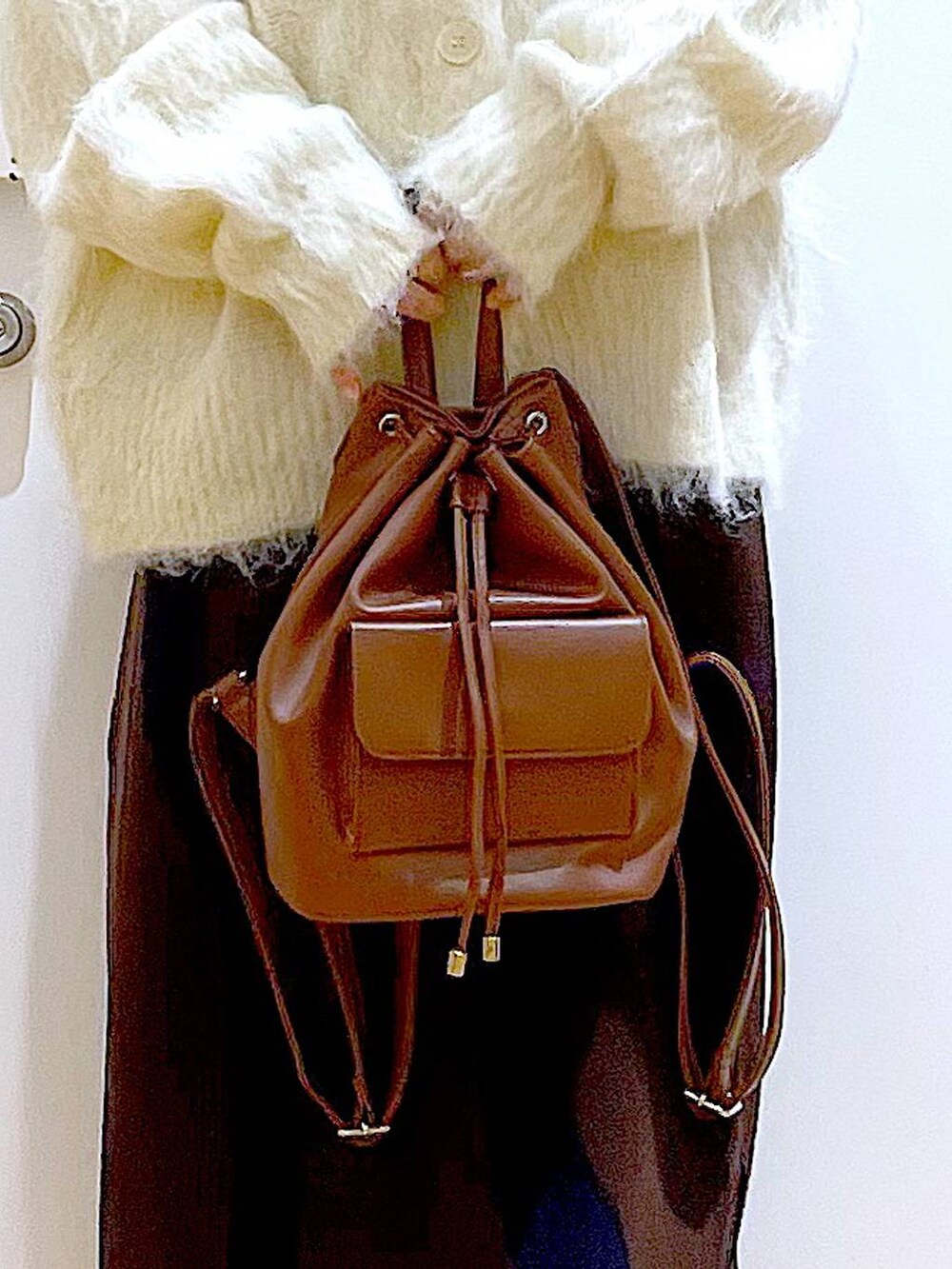 ベージュ系のニット/セーター、ブラウン系のバックパック/リュック、ブラウン系のスカートを着用したレディースの冬コーディネートの9枚目の写真