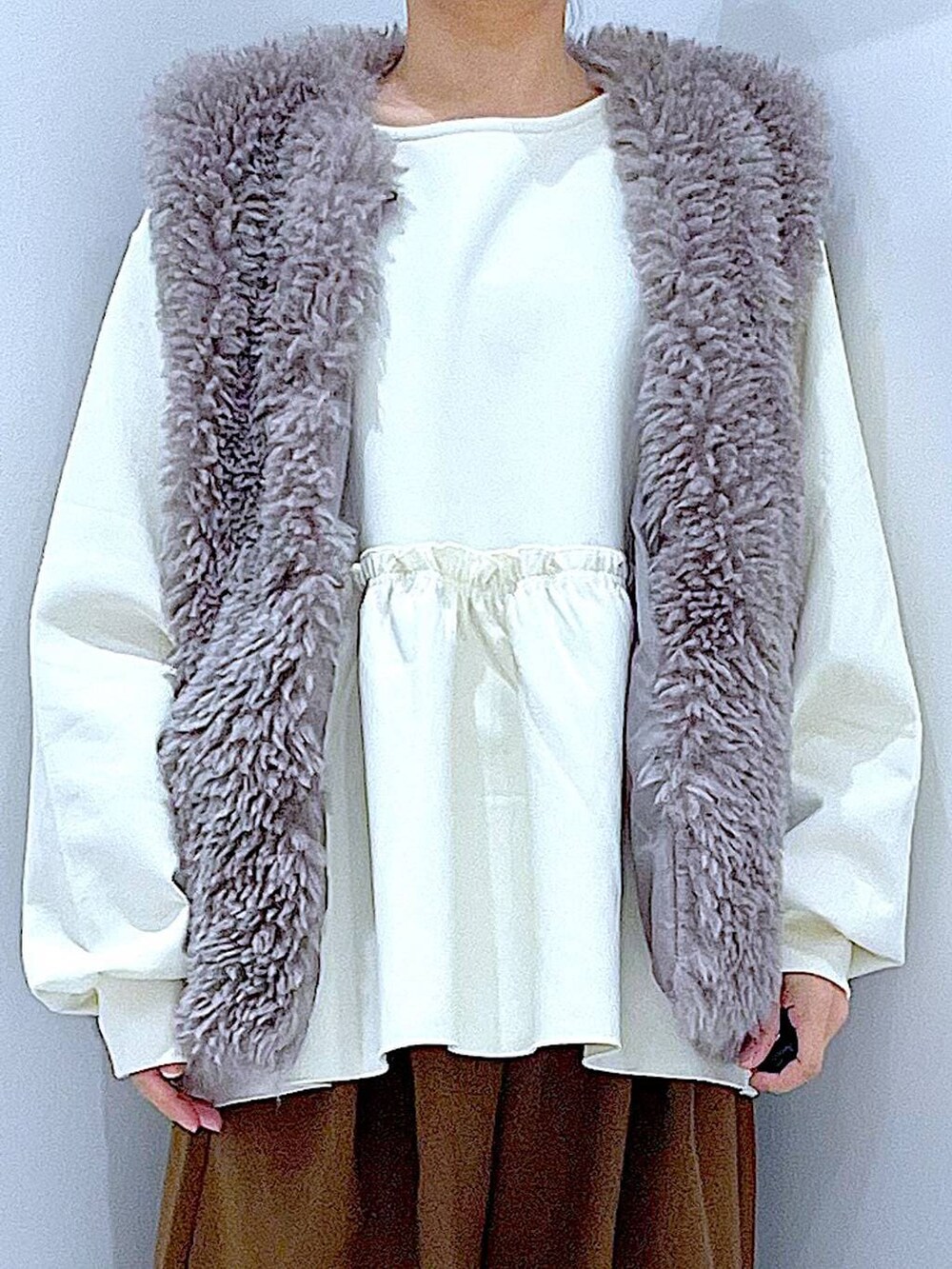 グレー系のベスト、ホワイト系のショルダーバッグ、ブラック系のブーツを着用したレディースの冬コーディネートの7枚目の写真