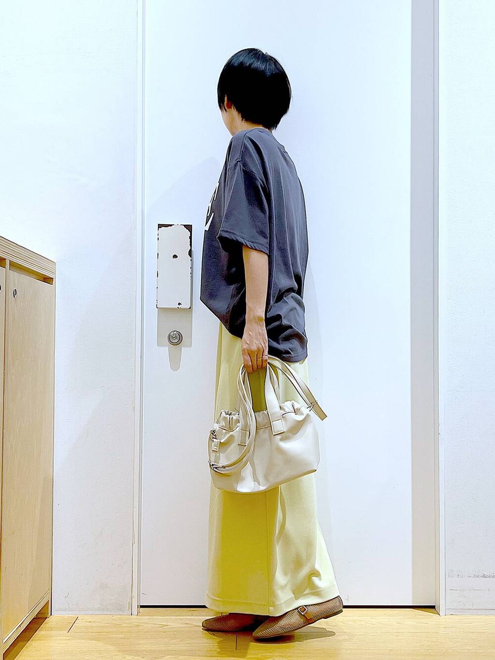 ホワイト系のショルダーバッグ、ベージュ系のパンプス、イエロー系のスカートを着用したレディースの夏コーディネートの3枚目の写真