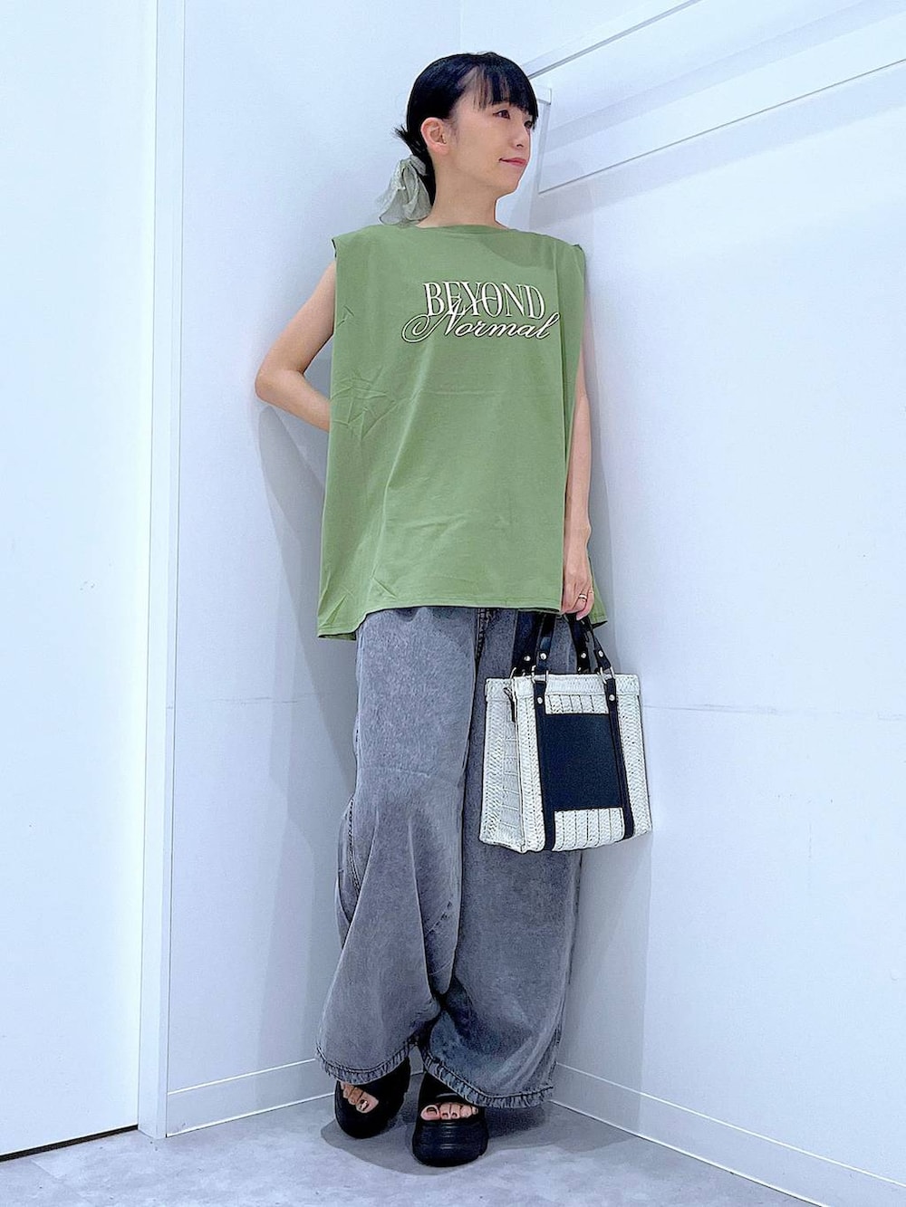 ホワイト系のショルダーバッグ、ブラック系のサンダル、グリーン系のTシャツ/カットソーを着用したレディースの夏コーディネートの2枚目の写真