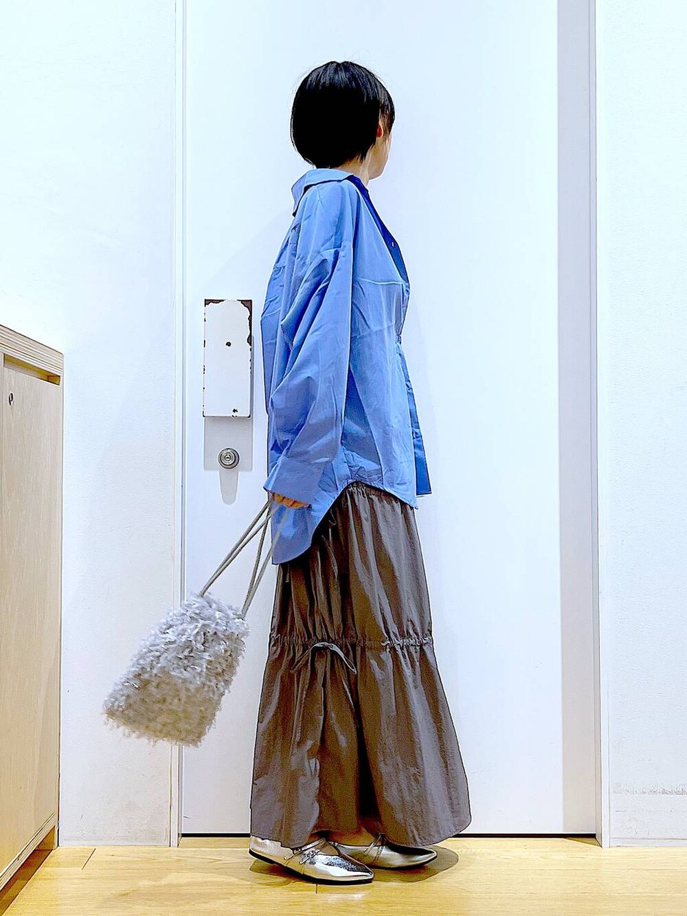 グレー系のショルダーバッグ、シルバー系のパンプス、グレー系のスカートを着用したレディースの秋コーディネートの4枚目の写真