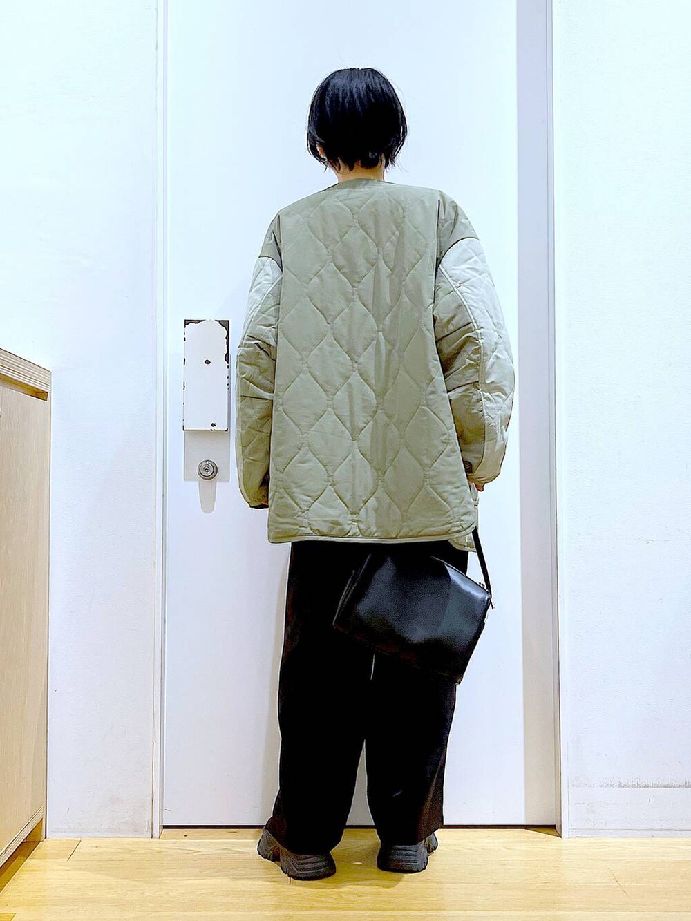 ブラック系のショルダーバッグ、ホワイト系のスウェット、ブラック系のブーツを着用したレディースの秋コーディネートの5枚目の写真