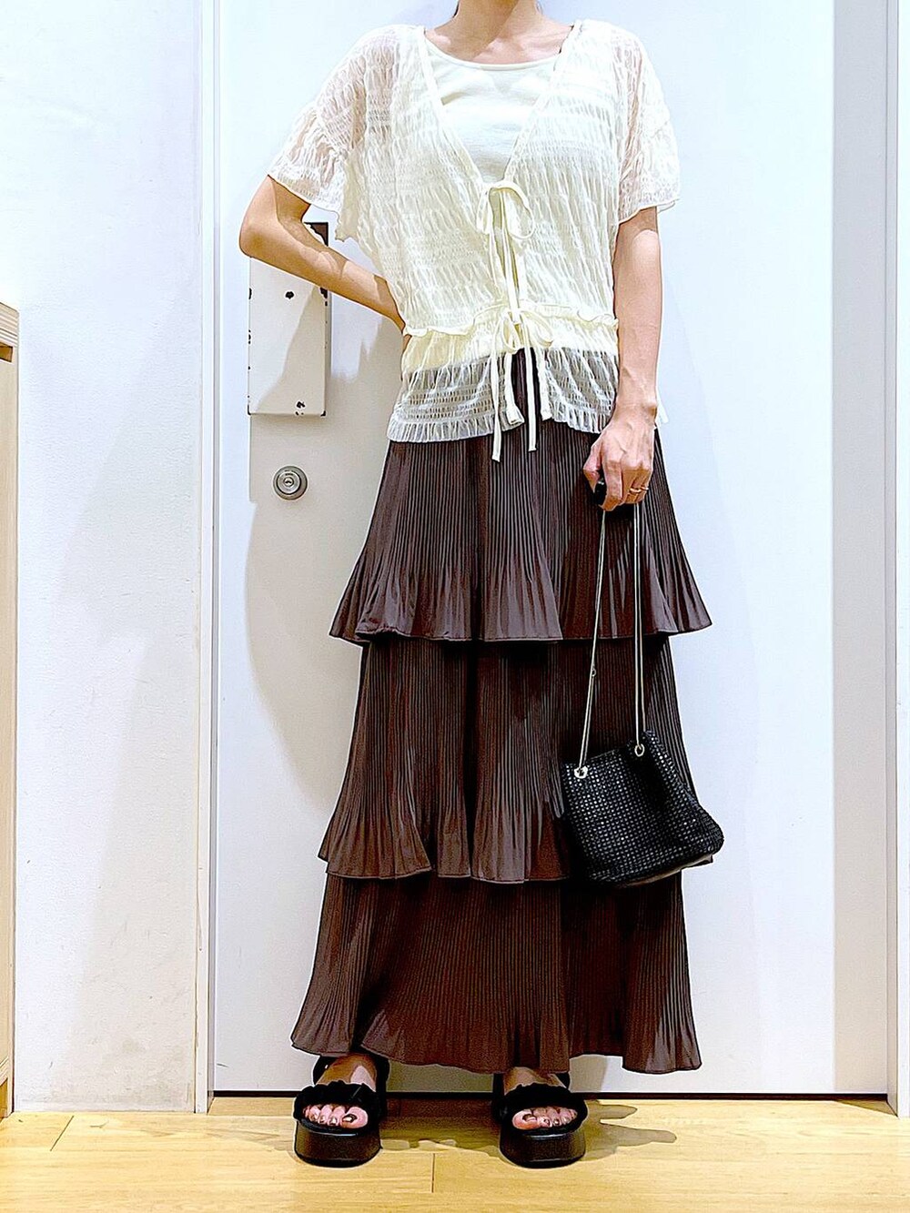 ブラウン系のスカート、ブラック系のサンダル、ホワイト系のカーディガン/ボレロを着用したレディースの夏コーディネートの6枚目の写真