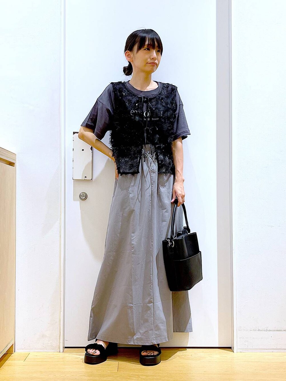 ブラック系のサンダル、ブラック系のショルダーバッグ、グレー系のスカートを着用したレディースの秋コーディネートの2枚目の写真