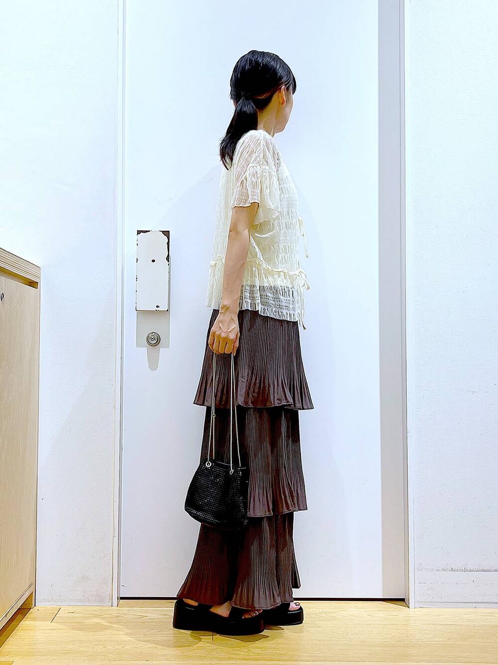 ブラウン系のスカート、ブラック系のサンダル、ホワイト系のカーディガン/ボレロを着用したレディースの夏コーディネートの4枚目の写真