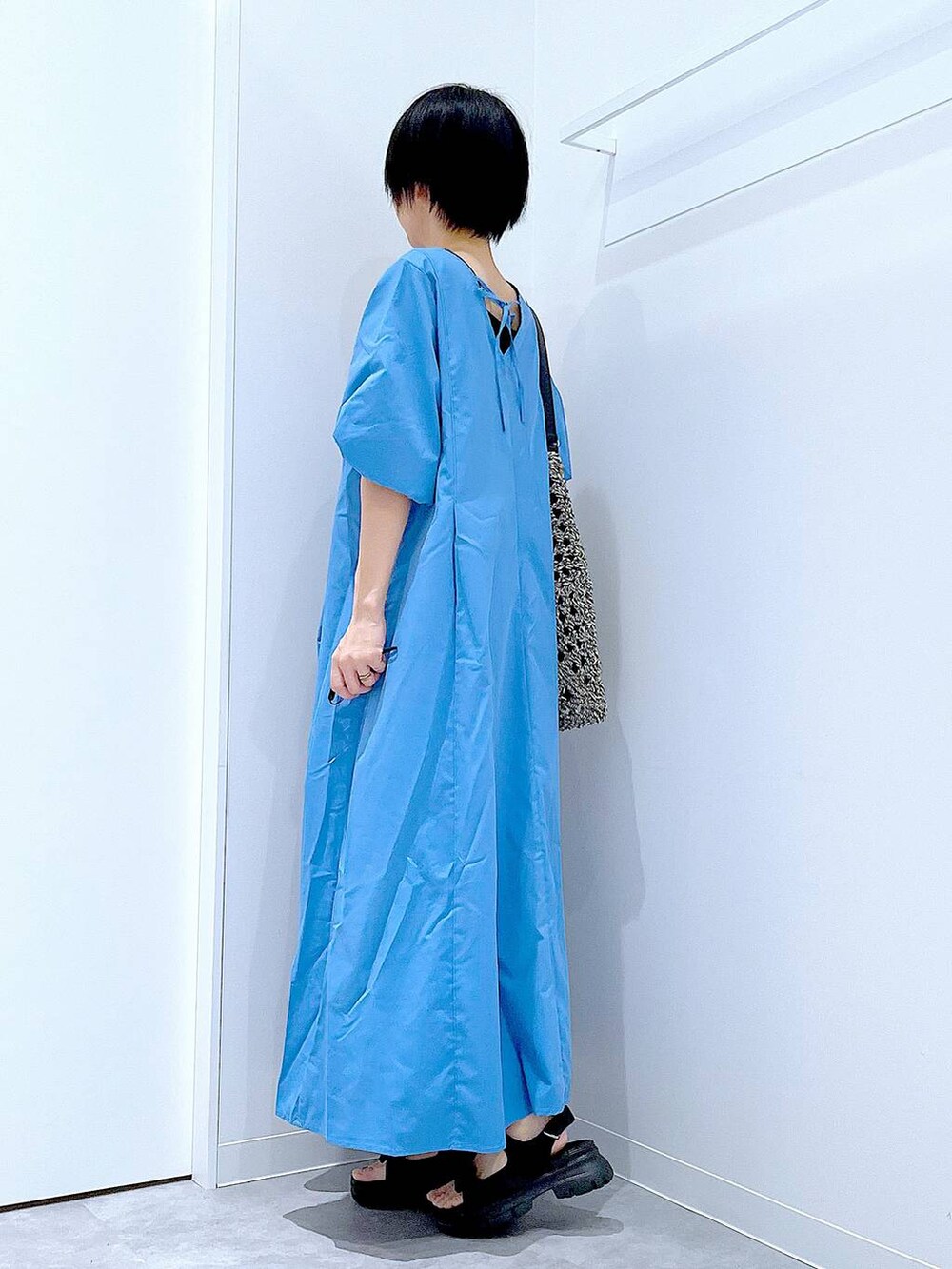 ブラック系のトートバッグ、ブラック系のサンダル、ブルー系のワンピースを着用したレディースの夏コーディネートの3枚目の写真