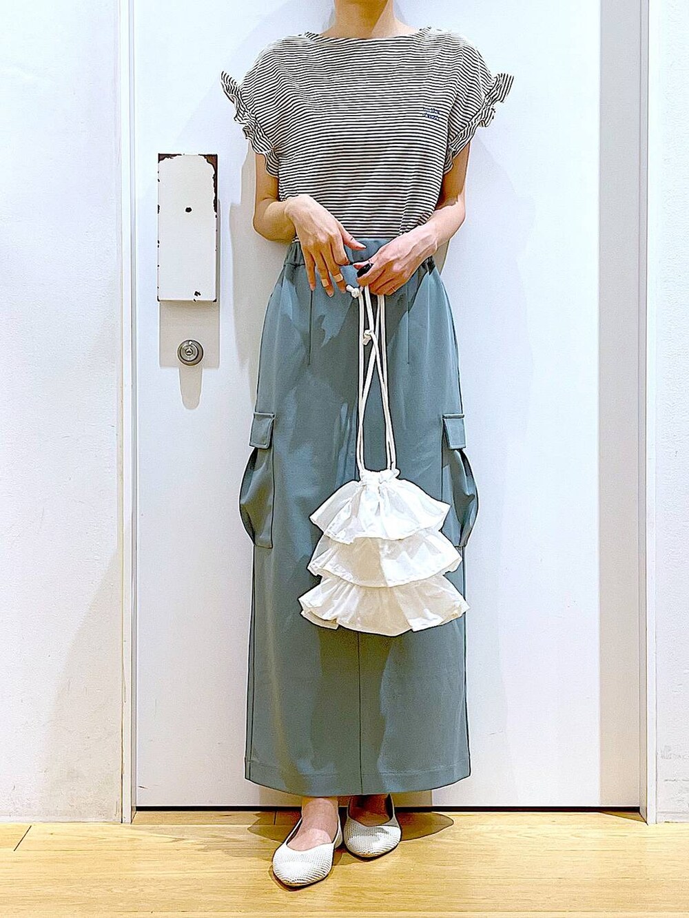 ホワイト系のショルダーバッグ、ホワイト系のパンプス、グリーン系のスカートを着用したレディースの春コーディネートの6枚目の写真