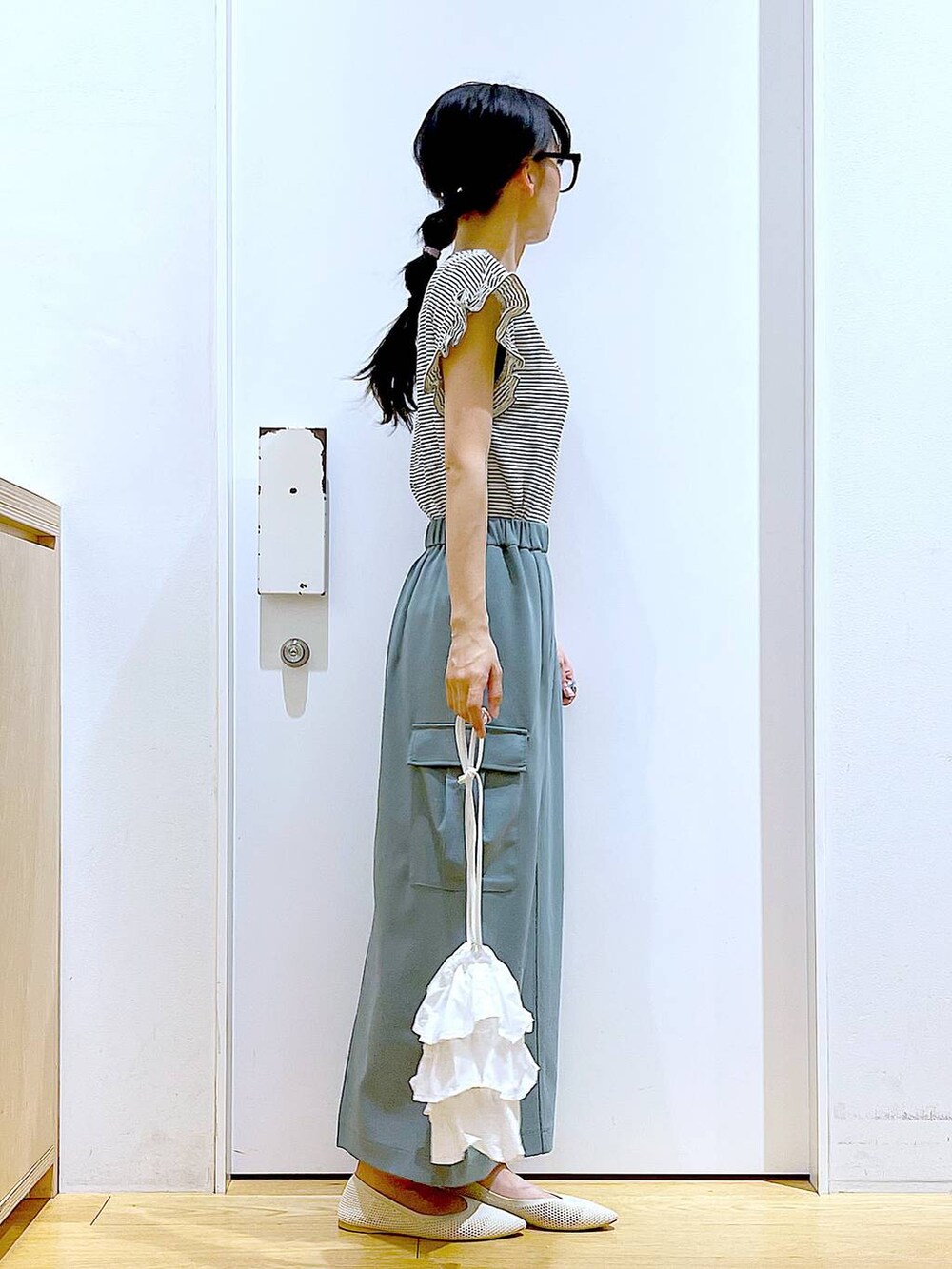 ホワイト系のショルダーバッグ、ホワイト系のパンプス、グリーン系のスカートを着用したレディースの春コーディネートの4枚目の写真