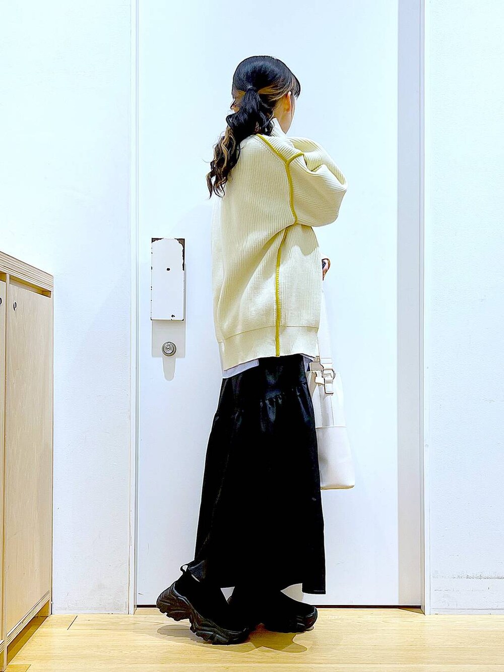 ホワイト系のショルダーバッグ、ホワイト系のカーディガン/ボレロ、ブラック系のスカートを着用したレディースの春コーディネートの4枚目の写真