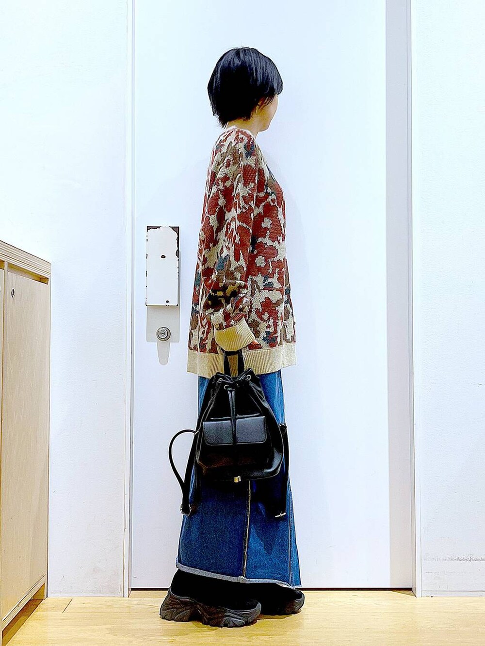 ブラック系のバックパック/リュック、ブルー系のデニムスカート、ブラック系のブーツを着用したレディースの冬コーディネートの4枚目の写真