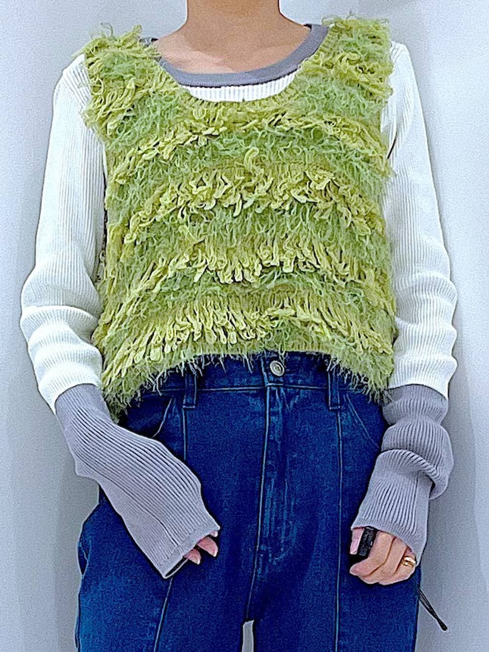 ブラック系のブーツ、ホワイト系のショルダーバッグ、グリーン系のベストを着用したレディースの春コーディネートの7枚目の写真