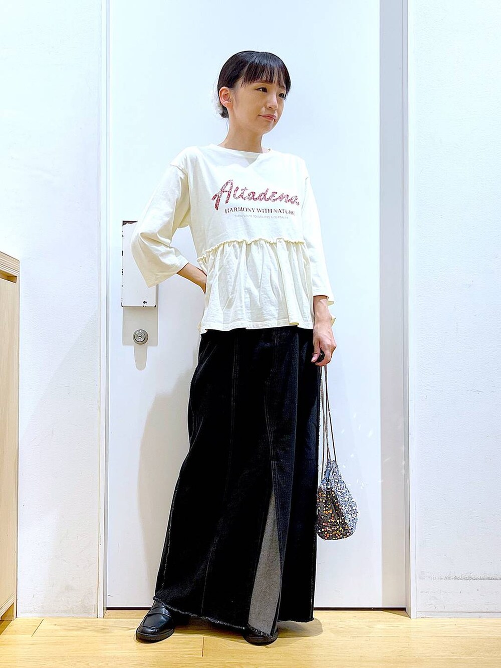 グレー系のショルダーバッグ、ブラック系のローファー、ベージュ系のTシャツ/カットソーを着用したレディースの秋コーディネートの2枚目の写真