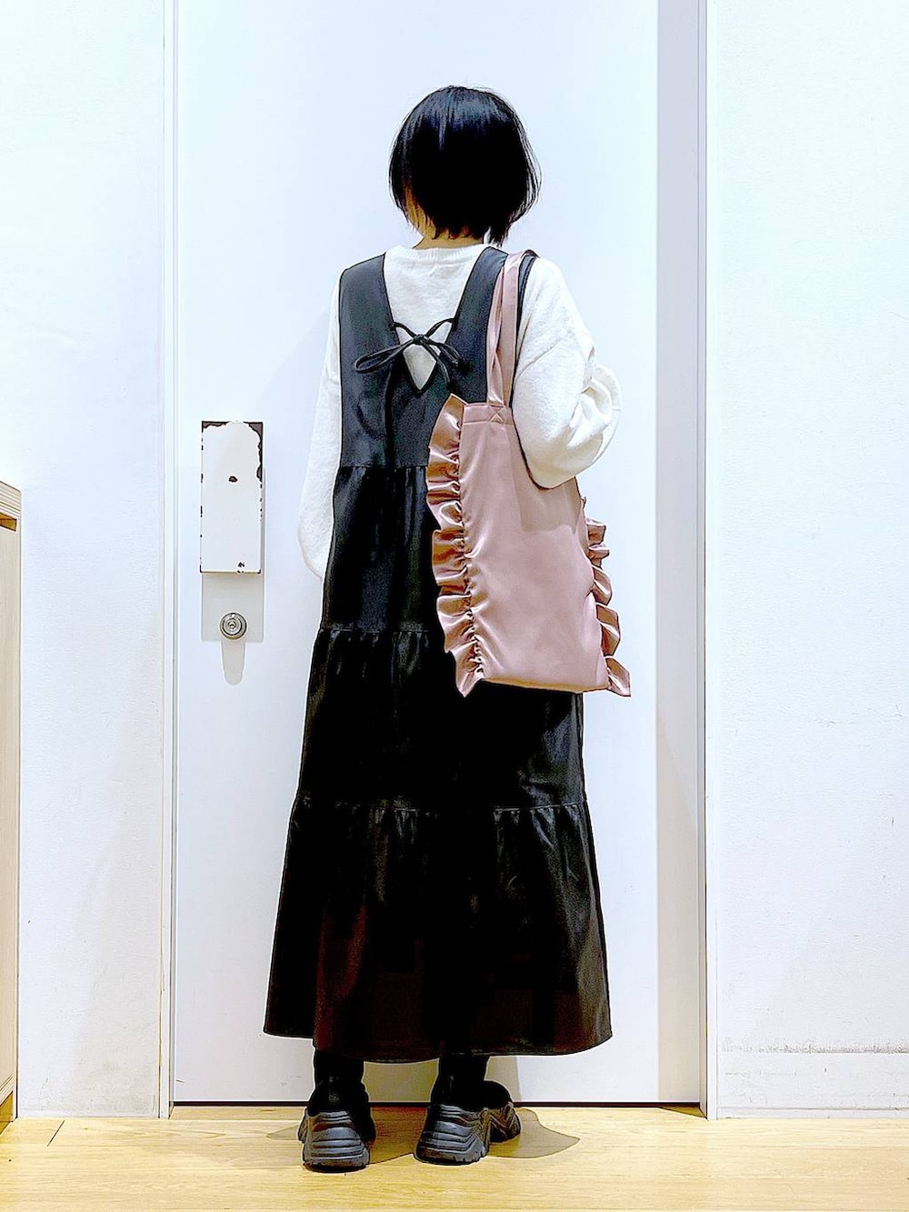 ブラック系のブーツ、ブラック系のワンピース、ピンク系のトートバッグを着用したレディースの冬コーディネートの5枚目の写真