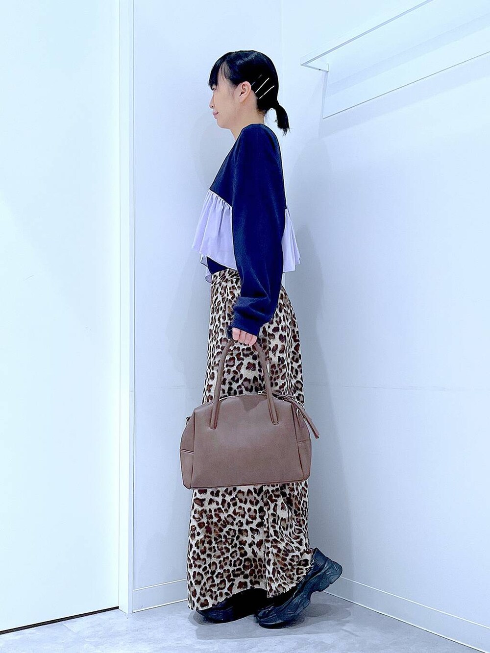 ブラック系のローファー、ブラウン系のボストンバッグ、ブラウン系のスカートを着用したレディースの秋コーディネートの3枚目の写真