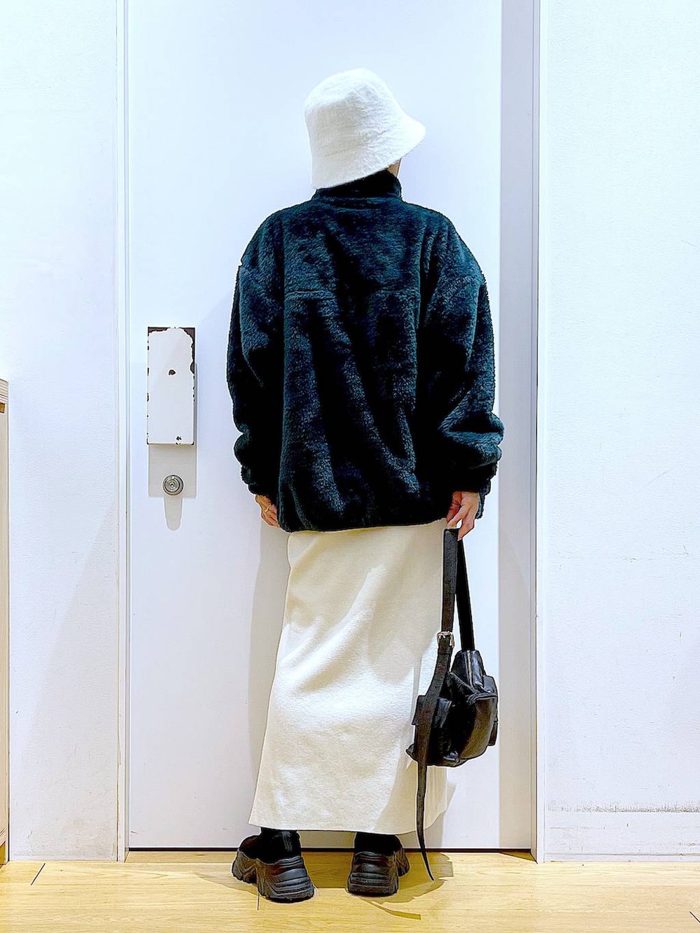 ブラック系のブーツ、ベージュ系のスカート、ブラック系のショルダーバッグを着用したレディースの冬コーディネートの5枚目の写真