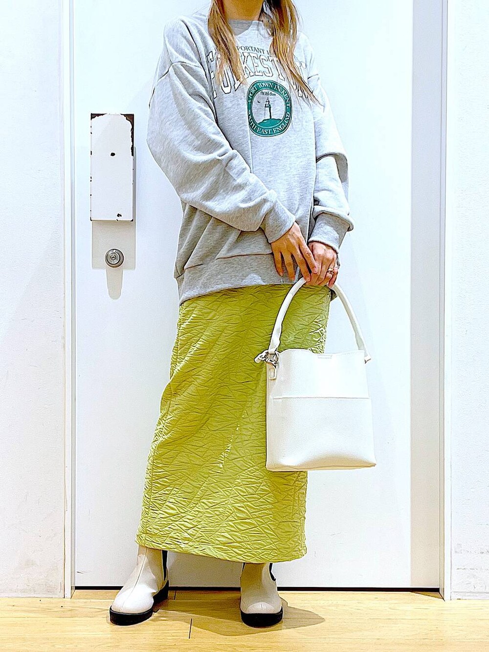 グリーン系のスカート、グレー系のスウェット、ホワイト系のショルダーバッグを着用したレディースの春コーディネートの6枚目の写真