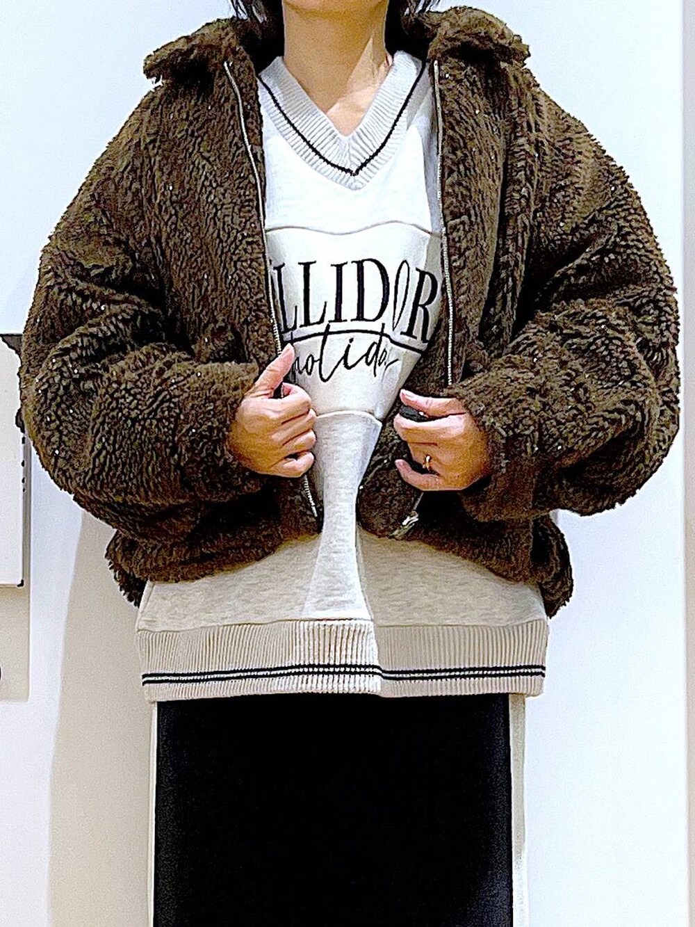 ブラック系のスカート、ブラック系のショルダーバッグ、ブラック系のブーツを着用したレディースの冬コーディネートの7枚目の写真