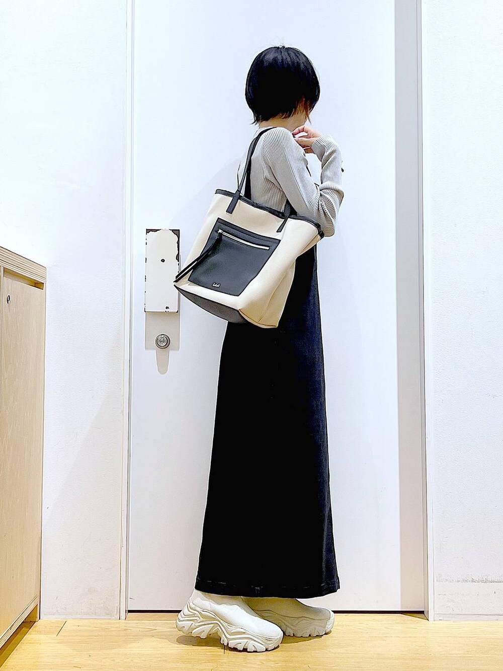 グレー系のジャンパースカート、ホワイト系のトートバッグ、グレー系のニット/セーターを着用したレディースの秋コーディネートの4枚目の写真