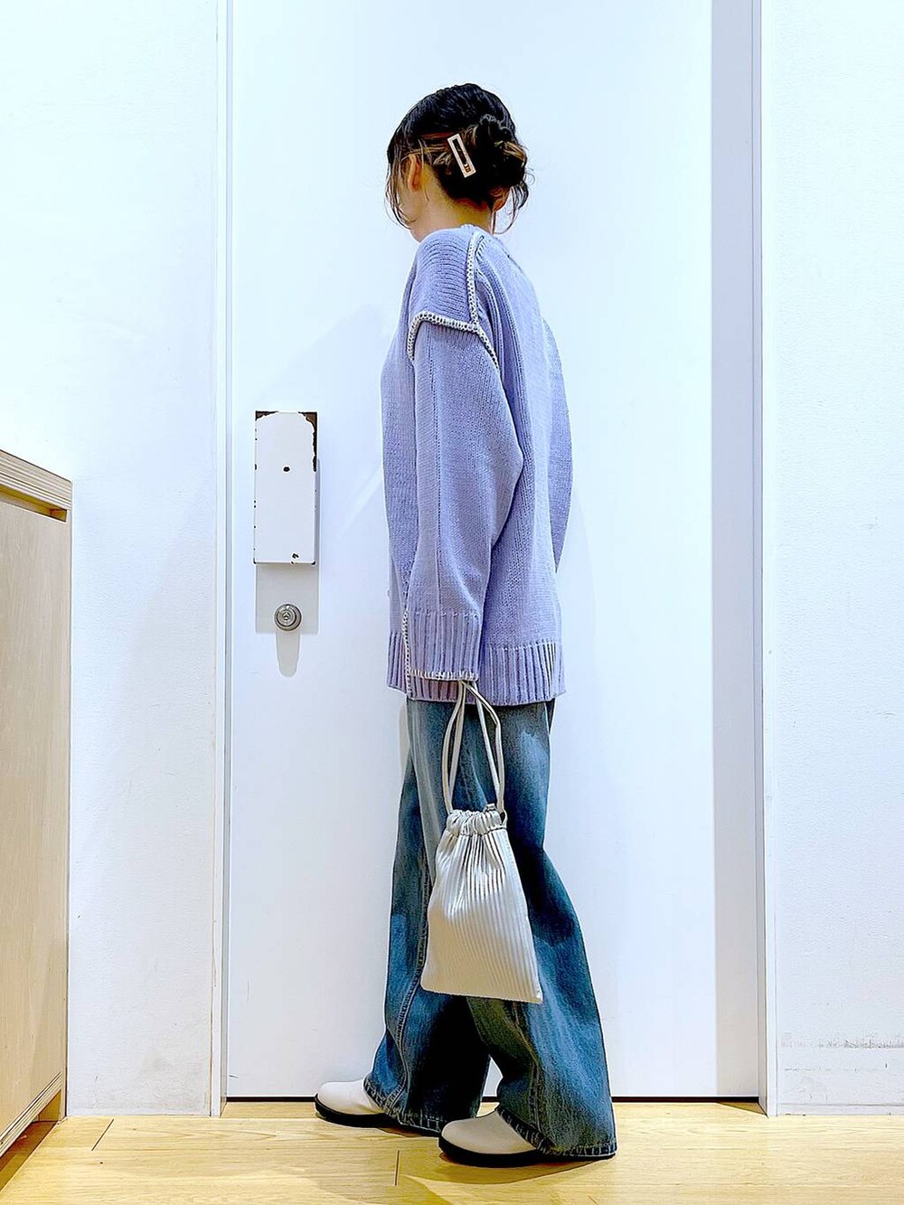 シルバー系のショルダーバッグ、ベージュ系のブーツ、ブルー系のデニムパンツを着用したレディースの冬コーディネートの3枚目の写真