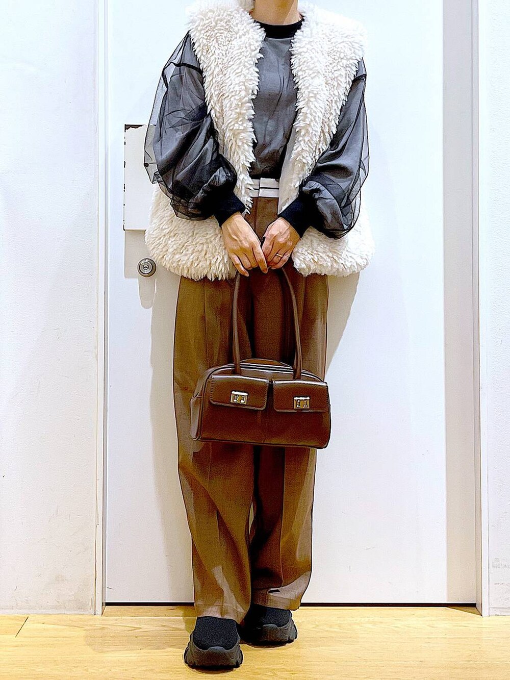 ベージュ系のベスト、ブラウン系のハンドバッグ、ブラック系のブーツを着用したレディースの冬コーディネートの6枚目の写真