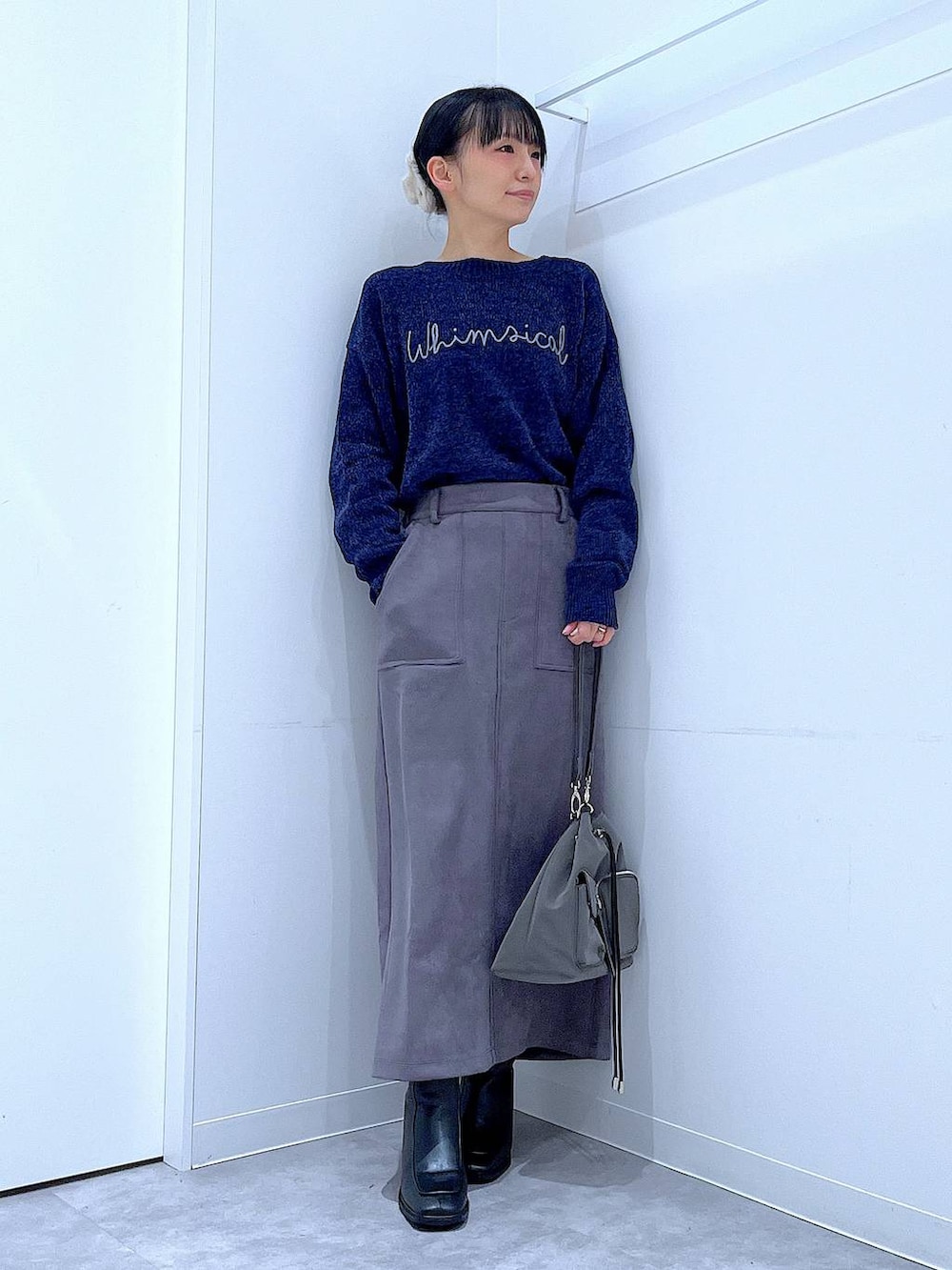 ブラック系のブーツ、ブルー系のニット/セーター、グレー系のスカートを着用したレディースの冬コーディネートの2枚目の写真