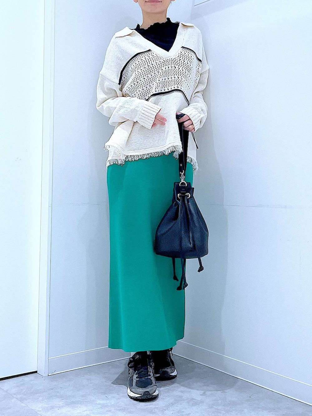 ブラック系のTシャツ/カットソー、グリーン系のスカート、ホワイト系のニット/セーターを着用したレディースの冬コーディネートの6枚目の写真