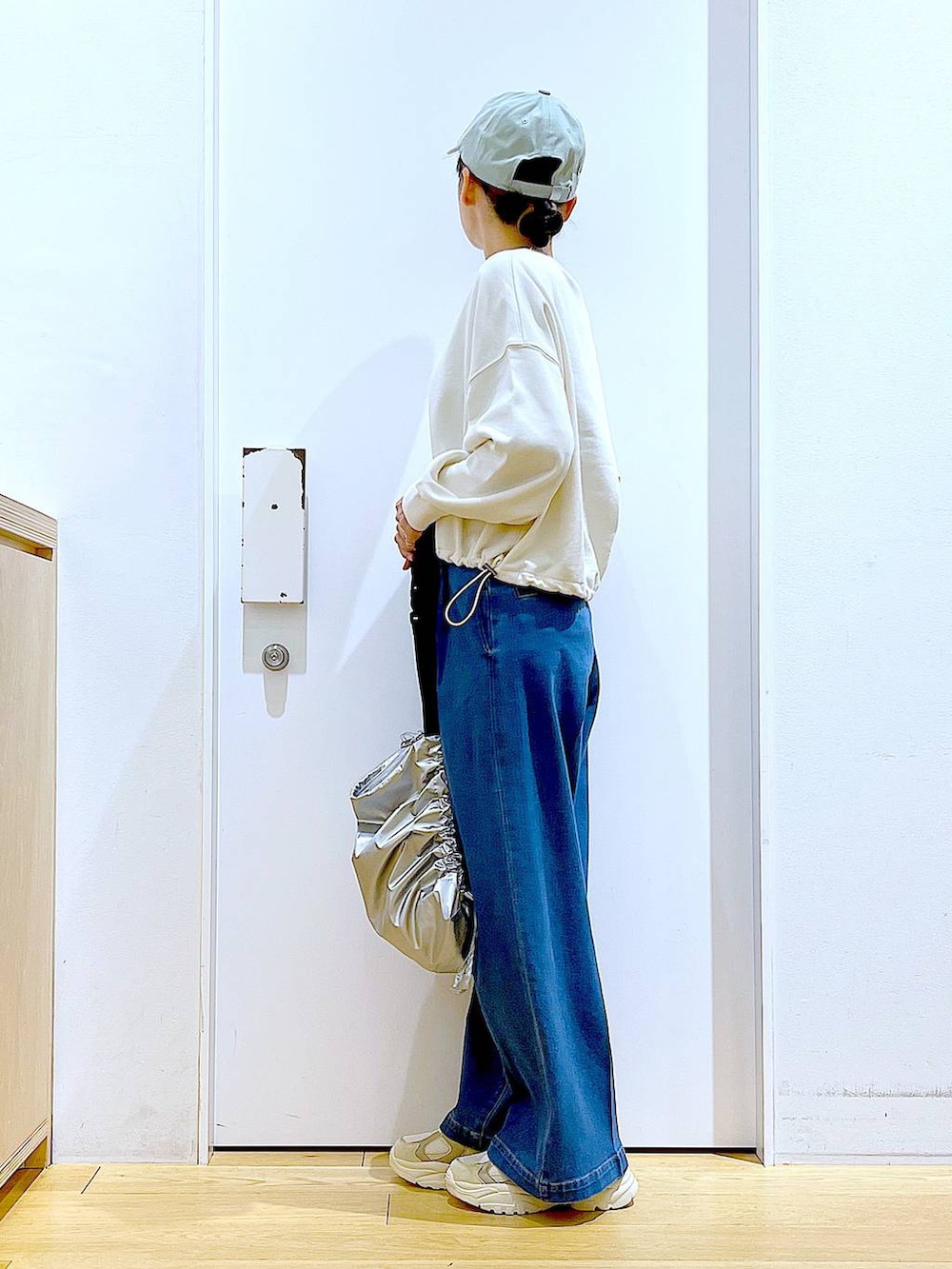 ホワイト系のスウェット、ブルー系のデニムパンツ、ベージュ系のスニーカーを着用したレディースの冬コーディネートの3枚目の写真