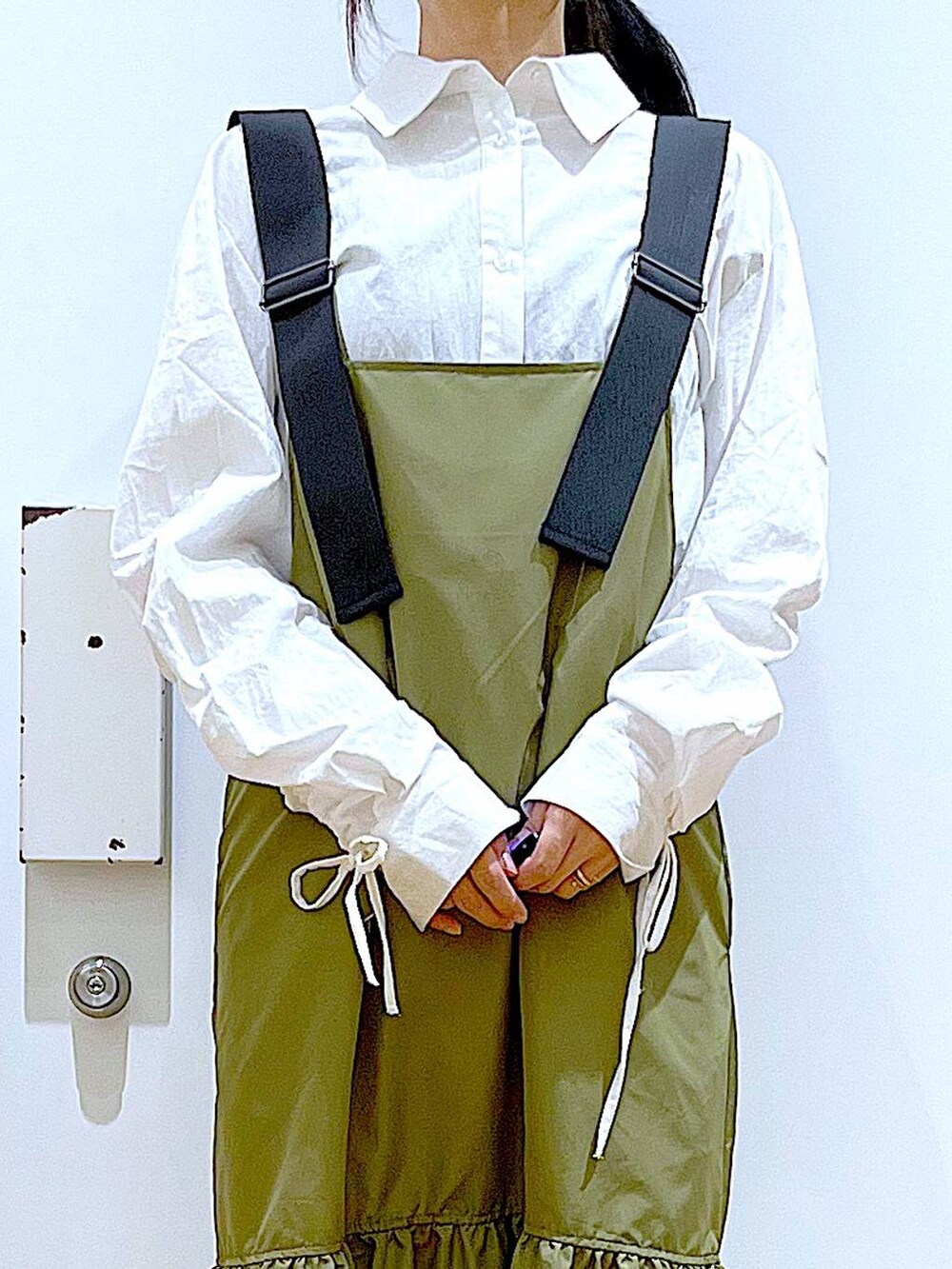 ブラック系のショルダーバッグ、グリーン系のワンピース、ホワイト系のシャツ/ブラウスを着用したレディースの春コーディネートの7枚目の写真