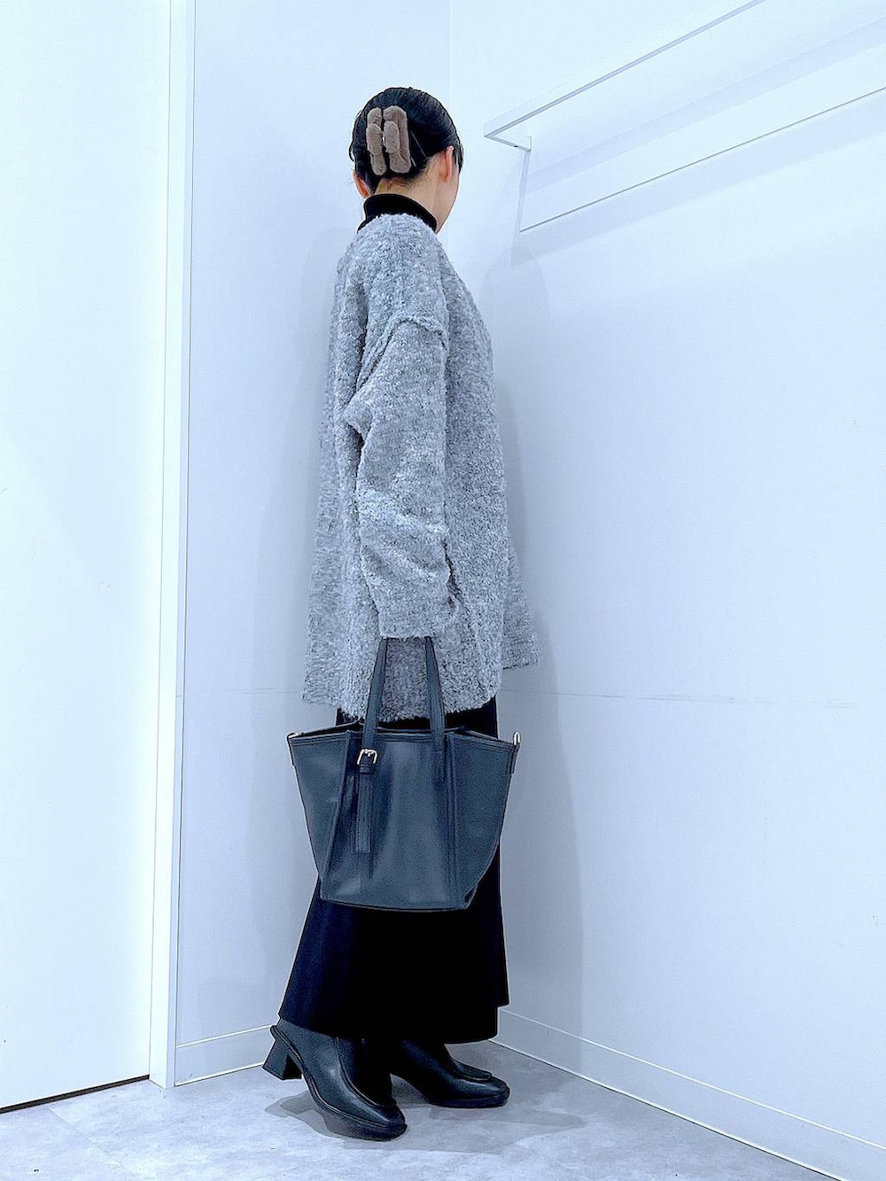 ブラック系のブーツ、グレー系のニット/セーター、ブラック系のスカートを着用したレディースの冬コーディネートの4枚目の写真