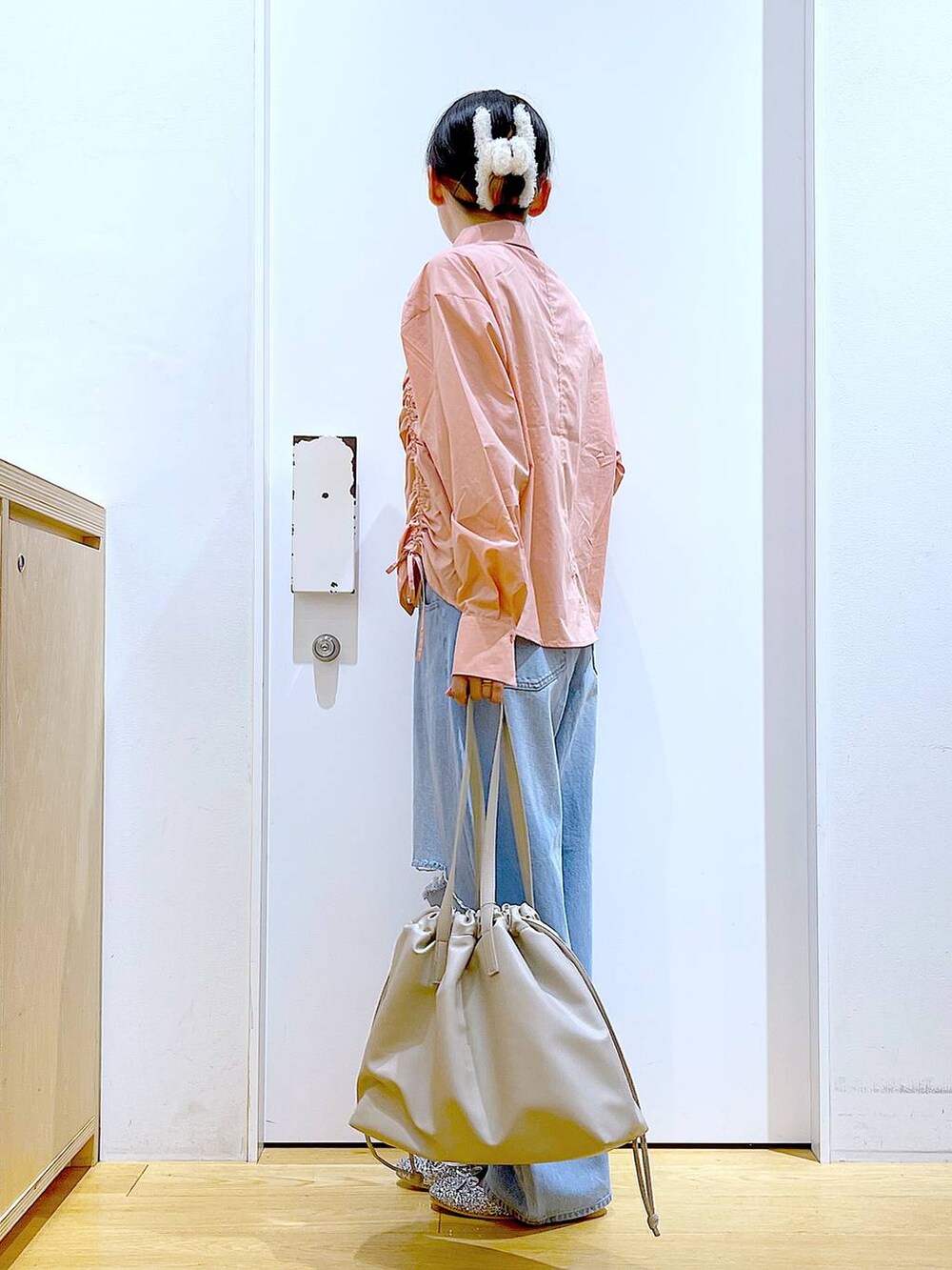 ベージュ系のトートバッグ、ブルー系のデニムパンツ、シルバー系のパンプスを着用したレディースの秋コーディネートの3枚目の写真