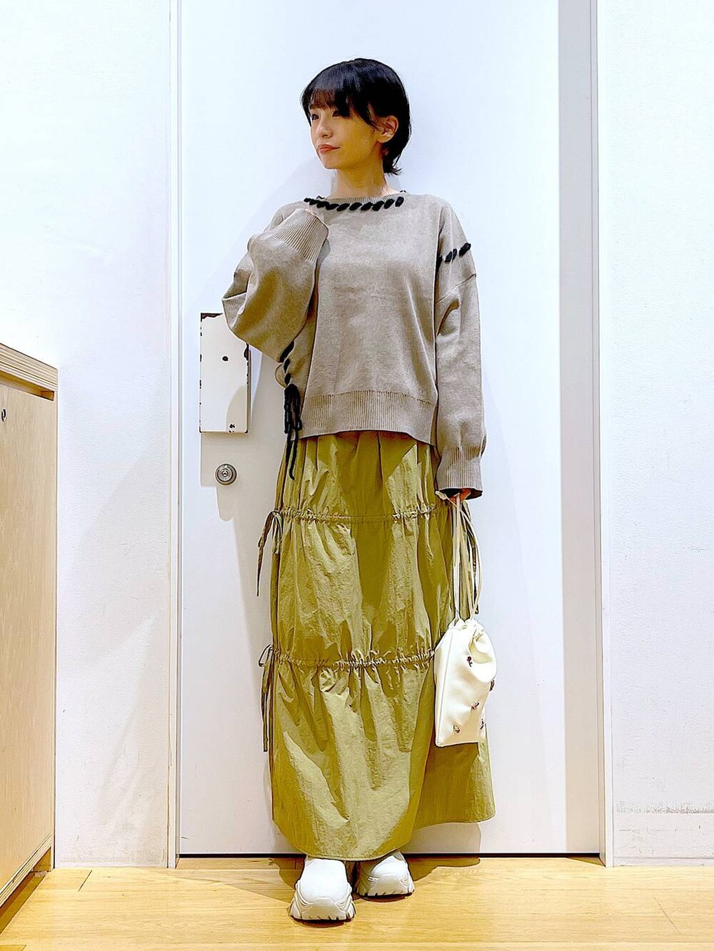 ホワイト系のショルダーバッグ、イエロー系のスカート、ベージュ系のブーツを着用したレディースの秋コーディネートの2枚目の写真