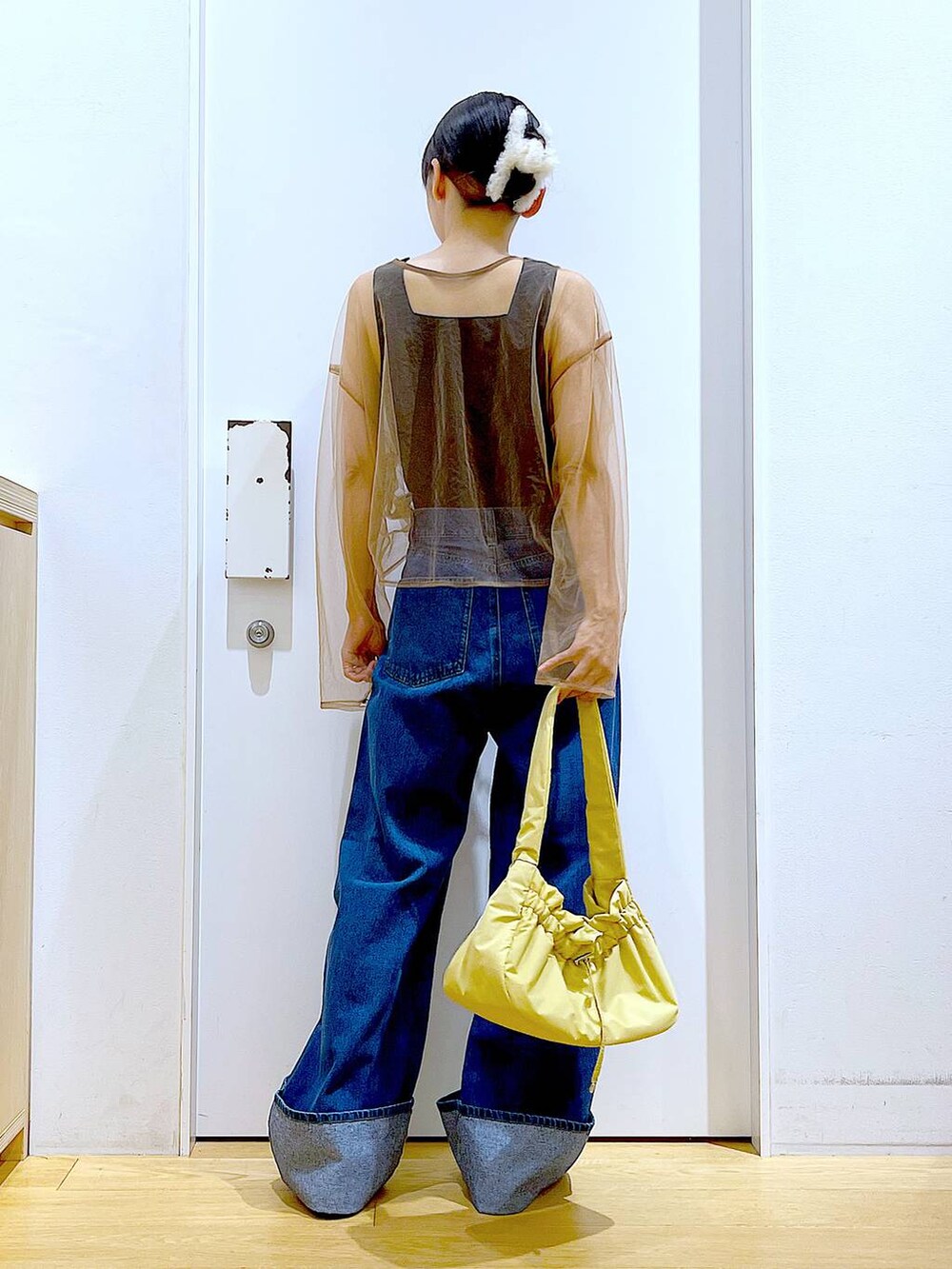 イエロー系のハンドバッグ、シルバー系のローファー、ブルー系のデニムパンツを着用したレディースの秋コーディネートの5枚目の写真