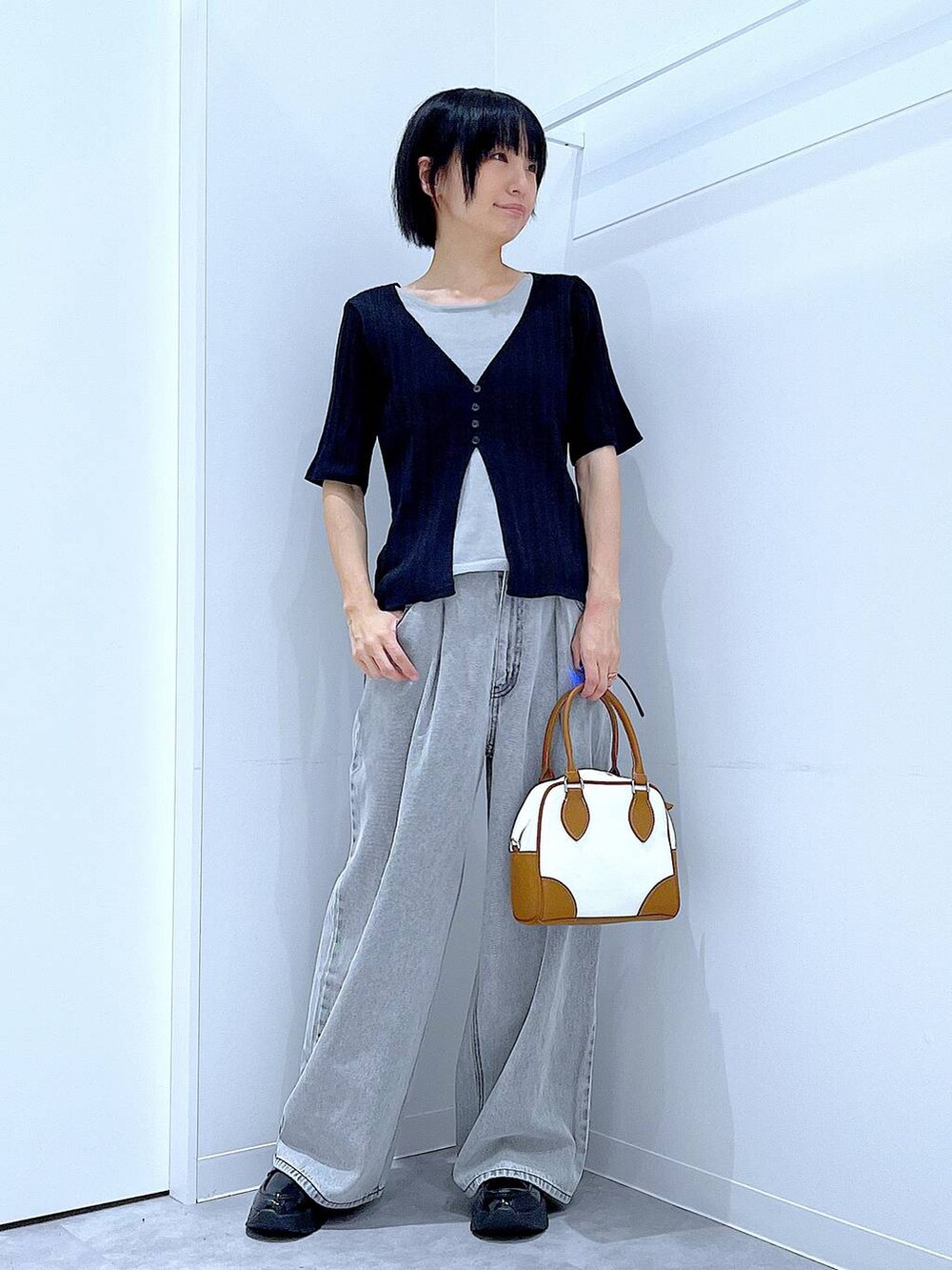 ブラック系のローファー、ホワイト系のハンドバッグ、ブラック系のニット/セーターを着用したレディースの秋コーディネートの2枚目の写真