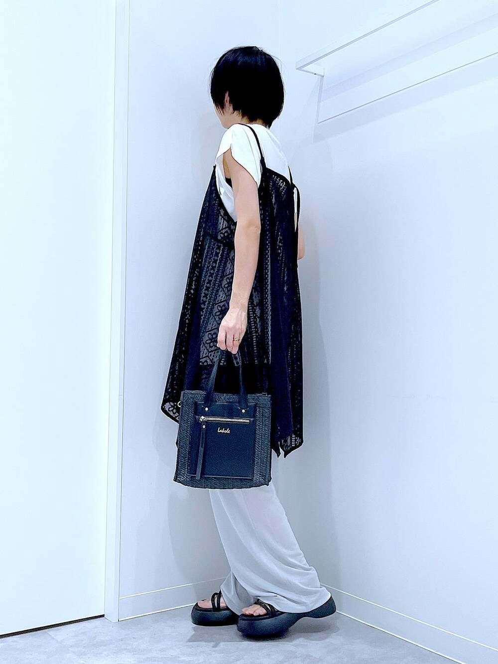 ブラック系のショルダーバッグ、ブラック系のサンダル、ホワイト系のTシャツ/カットソーを着用したレディースの夏コーディネートの3枚目の写真