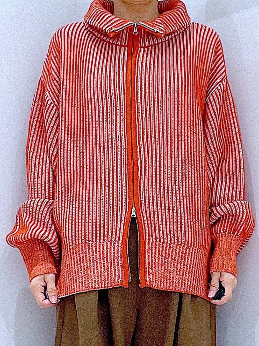 ブラック系のブーツ、オレンジ系のニット/セーター、ブラウン系のその他パンツを着用したレディースの冬コーディネートの7枚目の写真