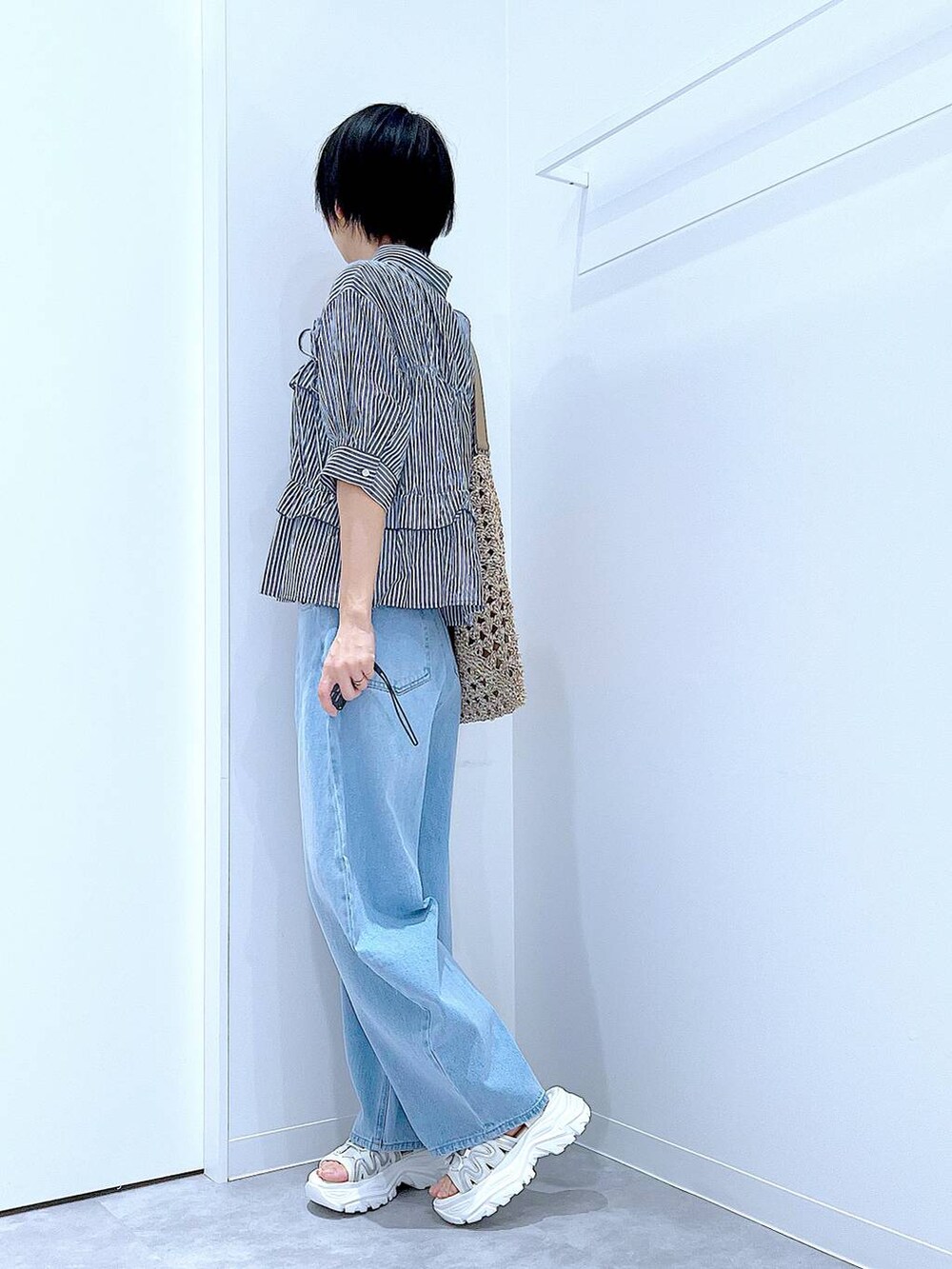 ブルー系のデニムパンツ、ベージュ系のトートバッグ、ホワイト系のスニーカーを着用したレディースの夏コーディネートの4枚目の写真