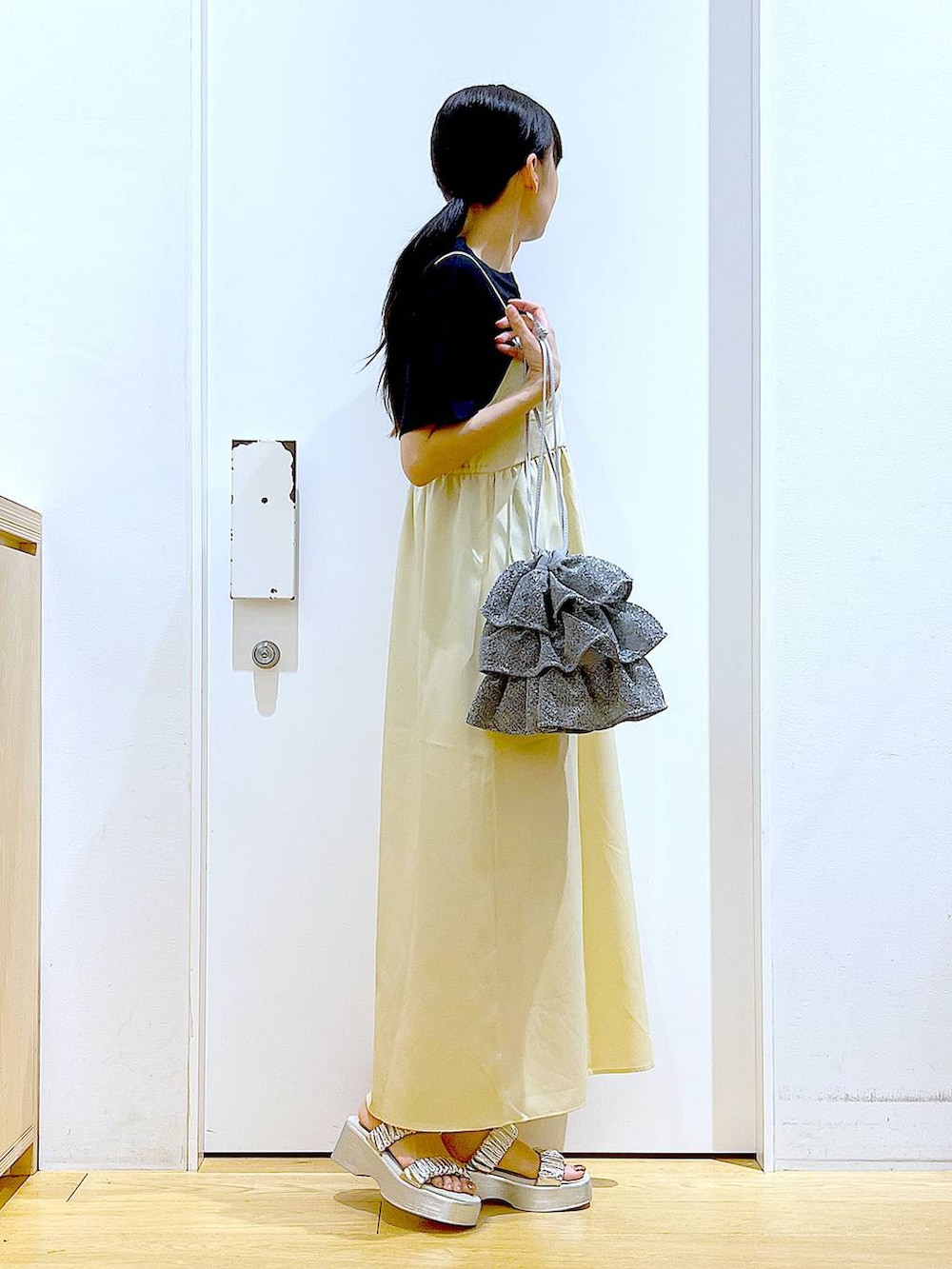 シルバー系のショルダーバッグ、シルバー系のサンダル、ブラック系のTシャツ/カットソーを着用したレディースの夏コーディネートの5枚目の写真