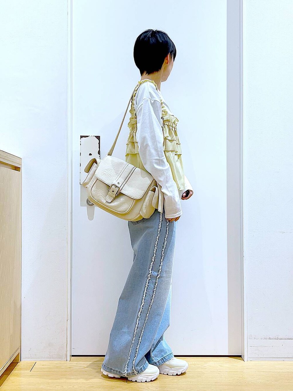 ホワイト系のスニーカー、ブルー系のデニムパンツ、ベージュ系のその他トップスを着用したレディースの春コーディネートの4枚目の写真