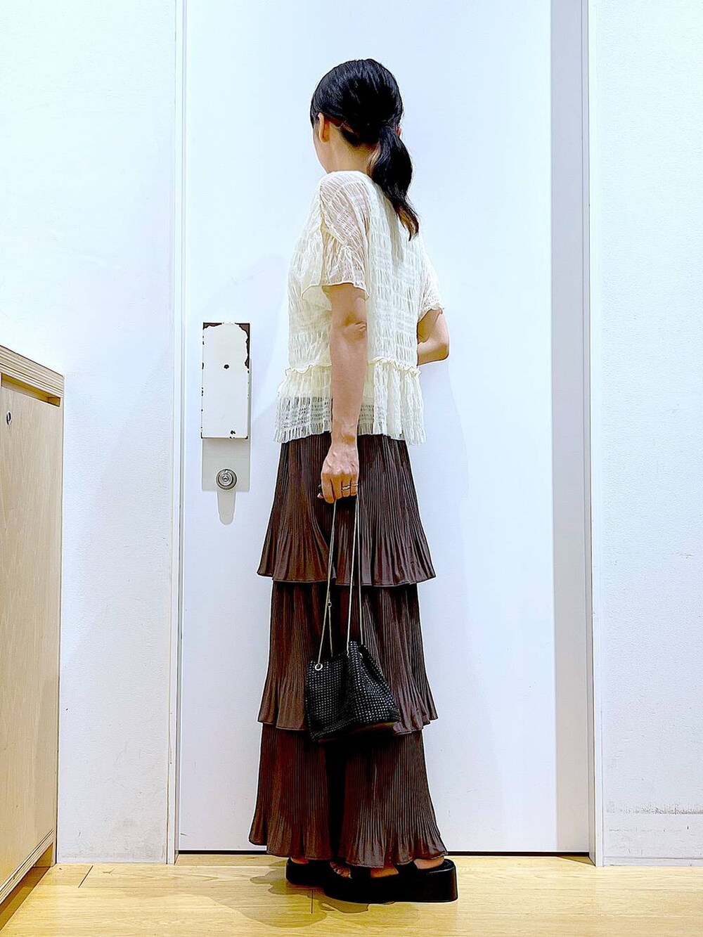 ブラウン系のスカート、ブラック系のサンダル、ホワイト系のカーディガン/ボレロを着用したレディースの夏コーディネートの3枚目の写真