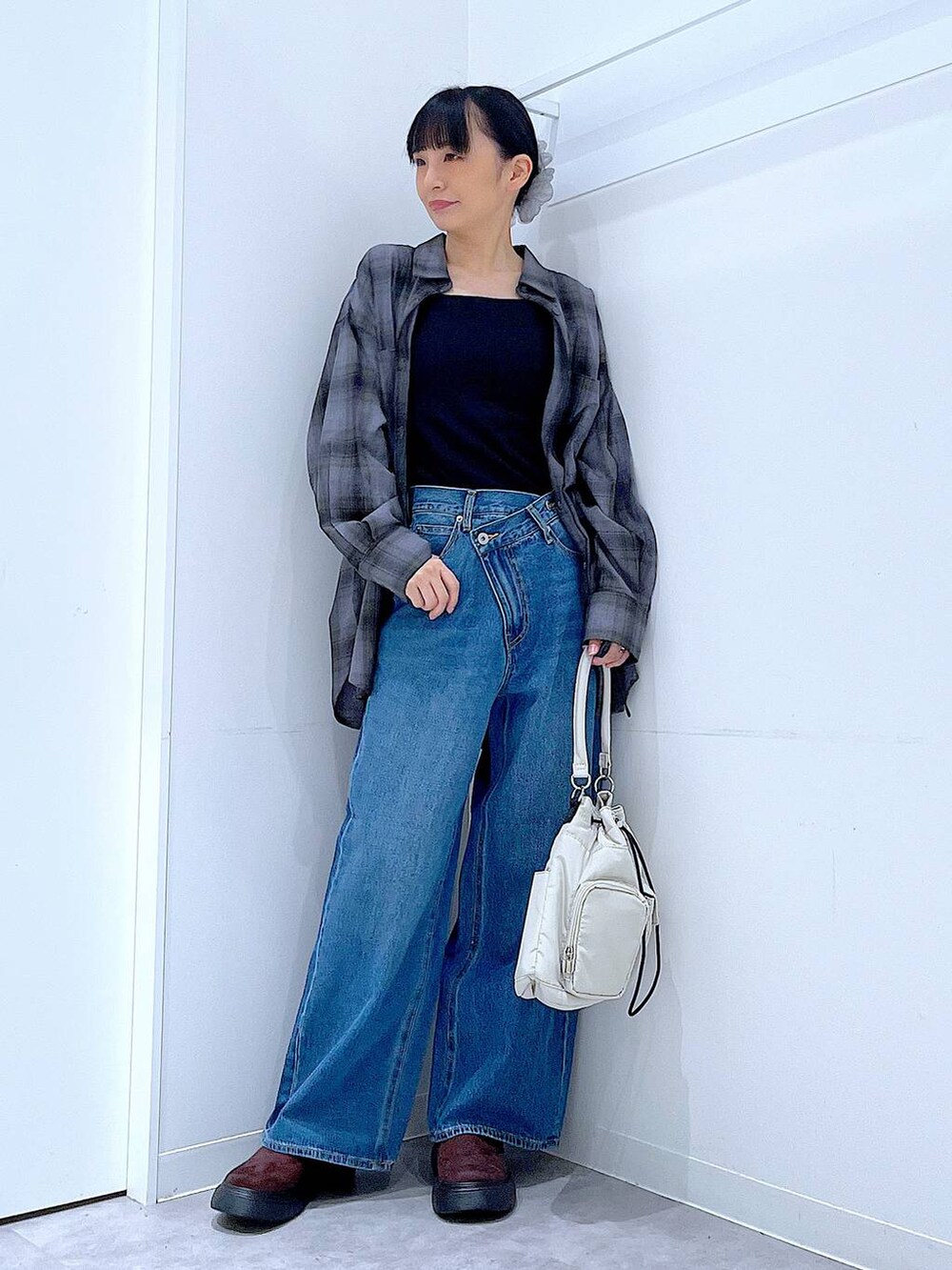 ブルー系のデニムパンツ、グレー系のシャツ/ブラウス、ホワイト系のハンドバッグを着用したレディースの秋コーディネートの2枚目の写真